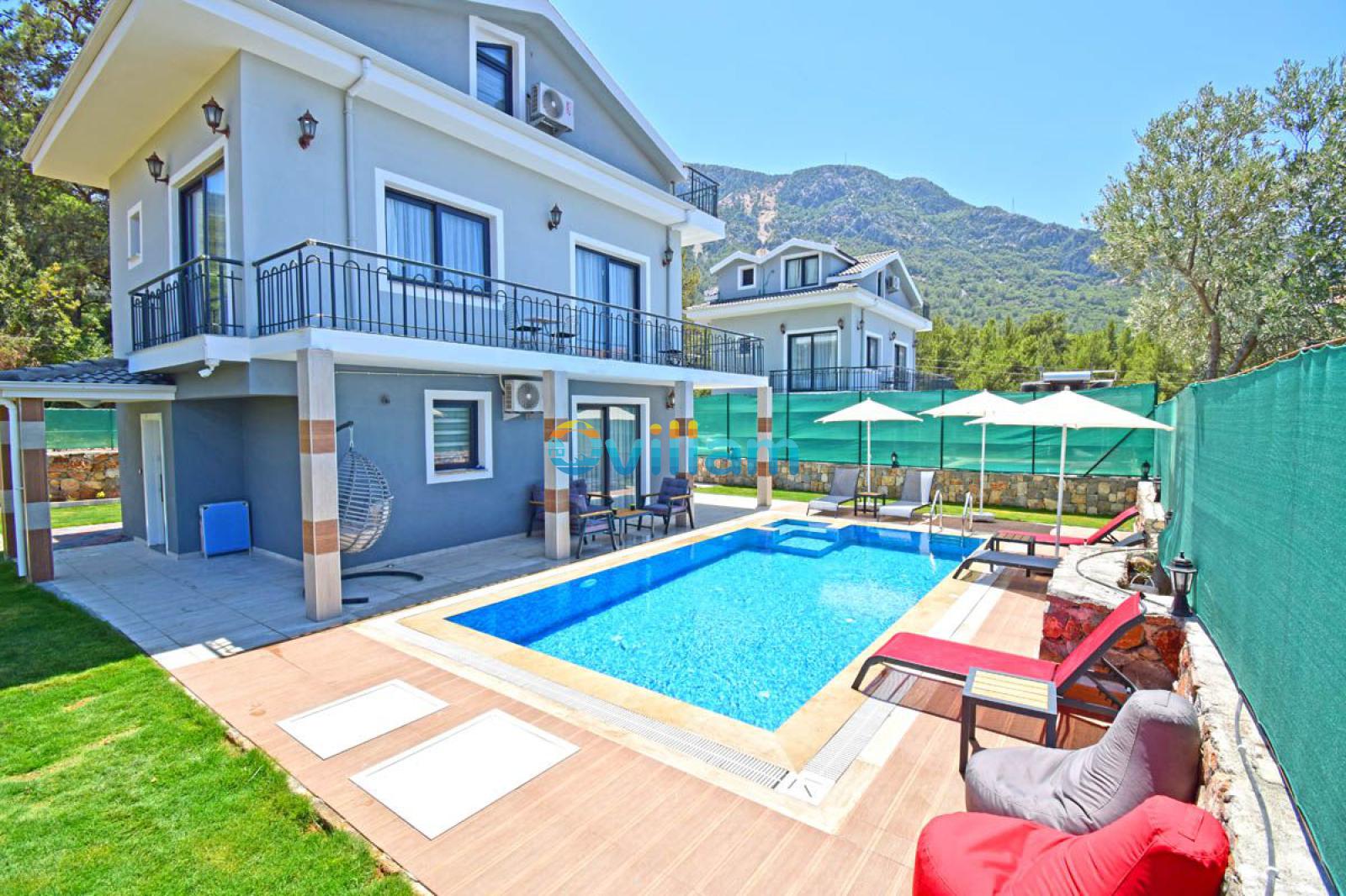 Şezlonglu havuz alanı ve gri villa dış cephesi.