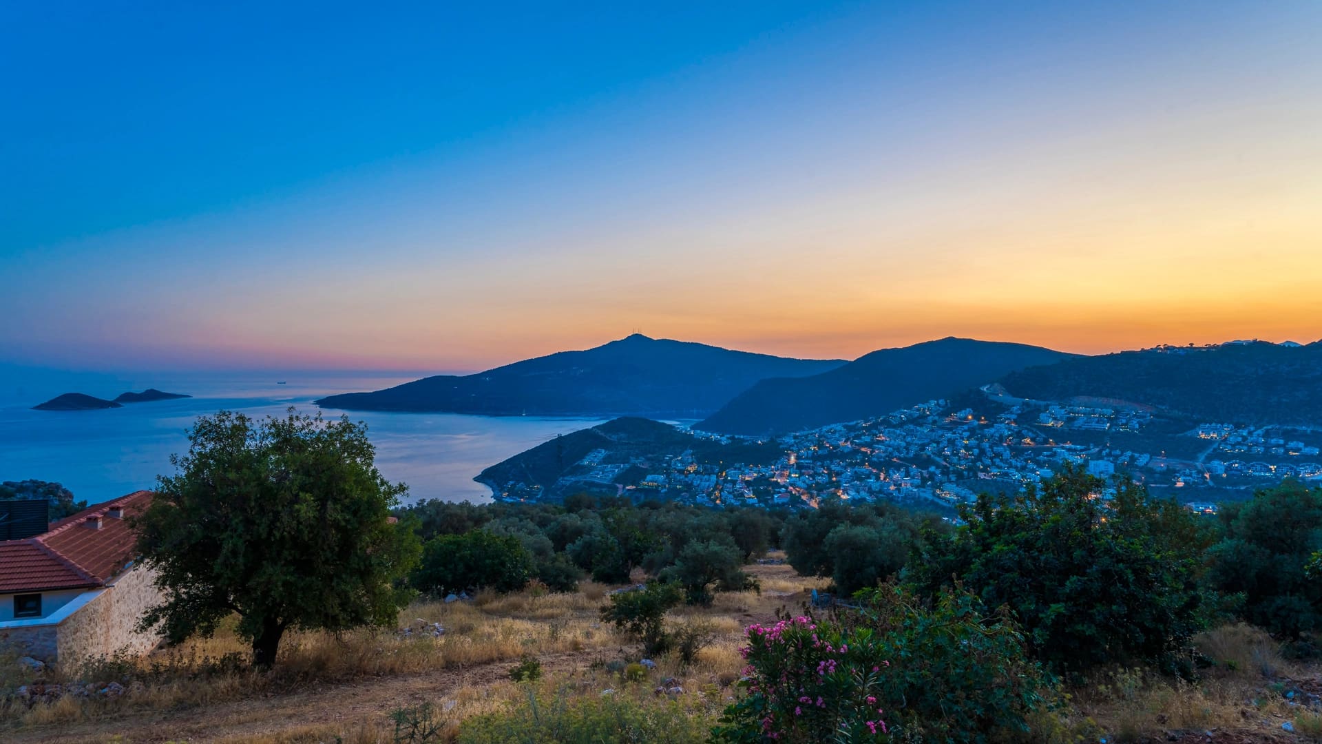 Gün batımında deniz, koy ve tepelerin panoramik manzarası.