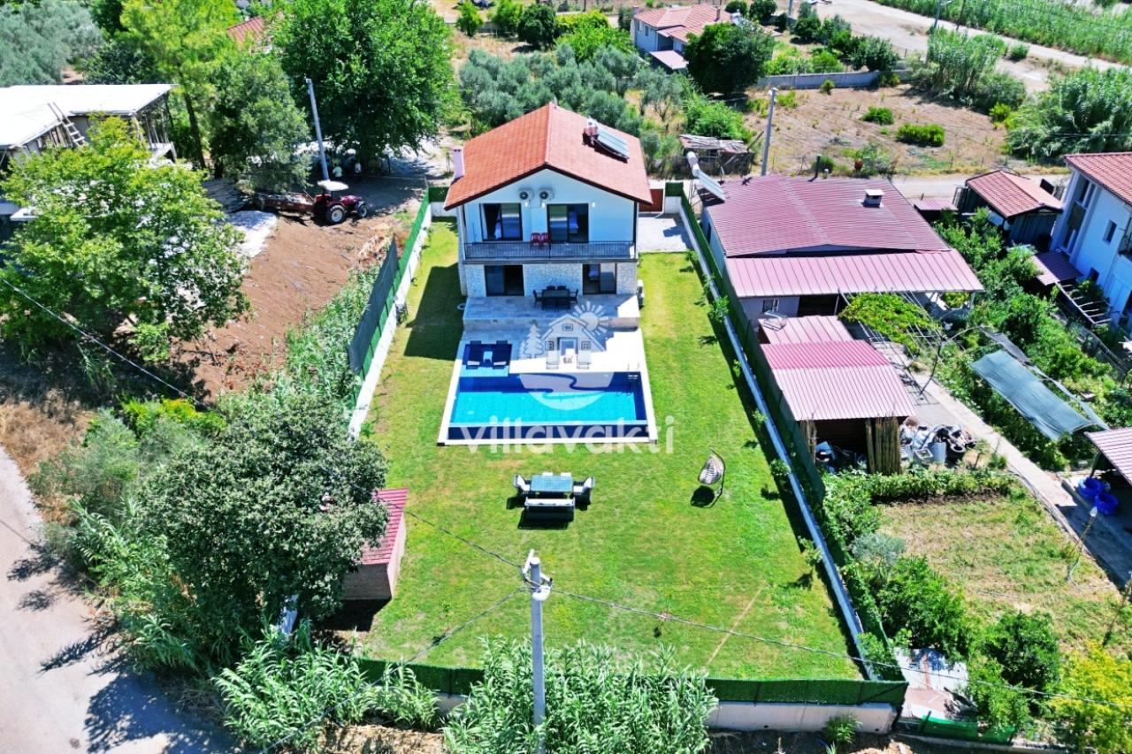 Bahçesinde havuz bulunan iki katlı villanın havadan görünümü.