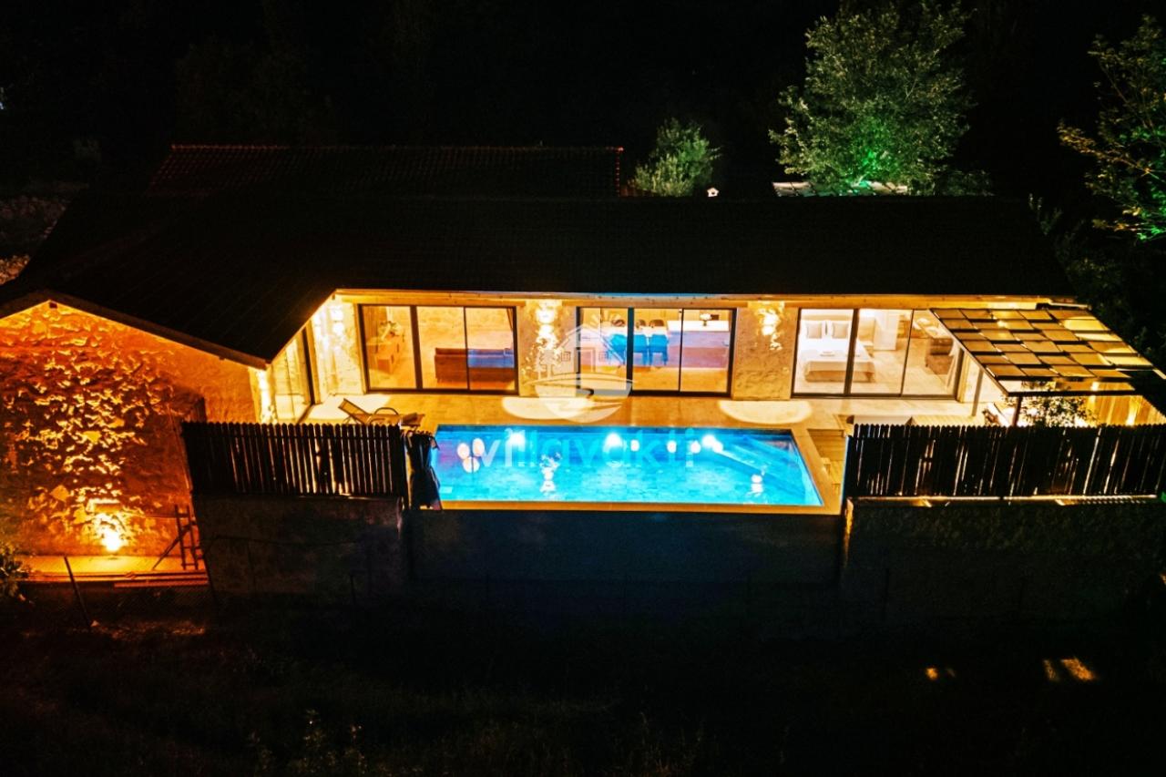 Gecesi aydınlatılmış havuz ve villa dış cephesi