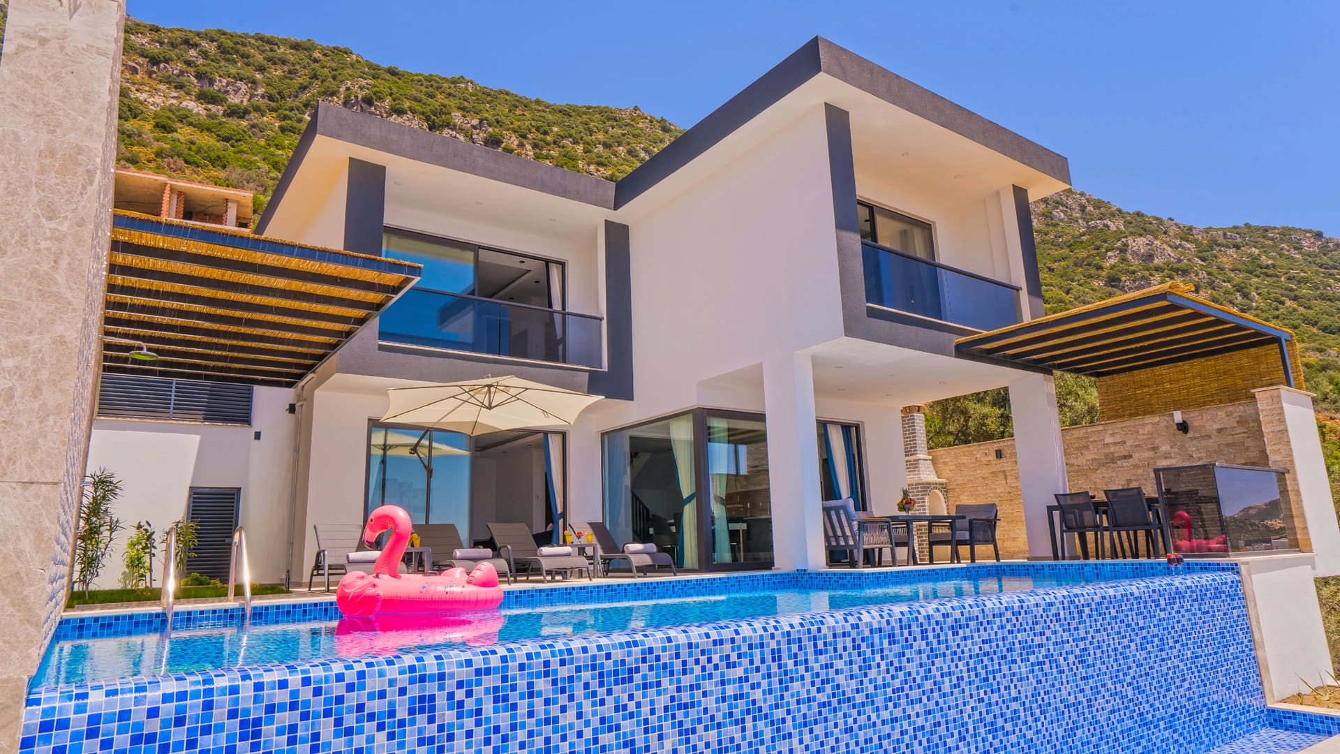 Beyaz dış cepheli, havuzlu ve pembe flamingo deniz yatağı bulunan villa.