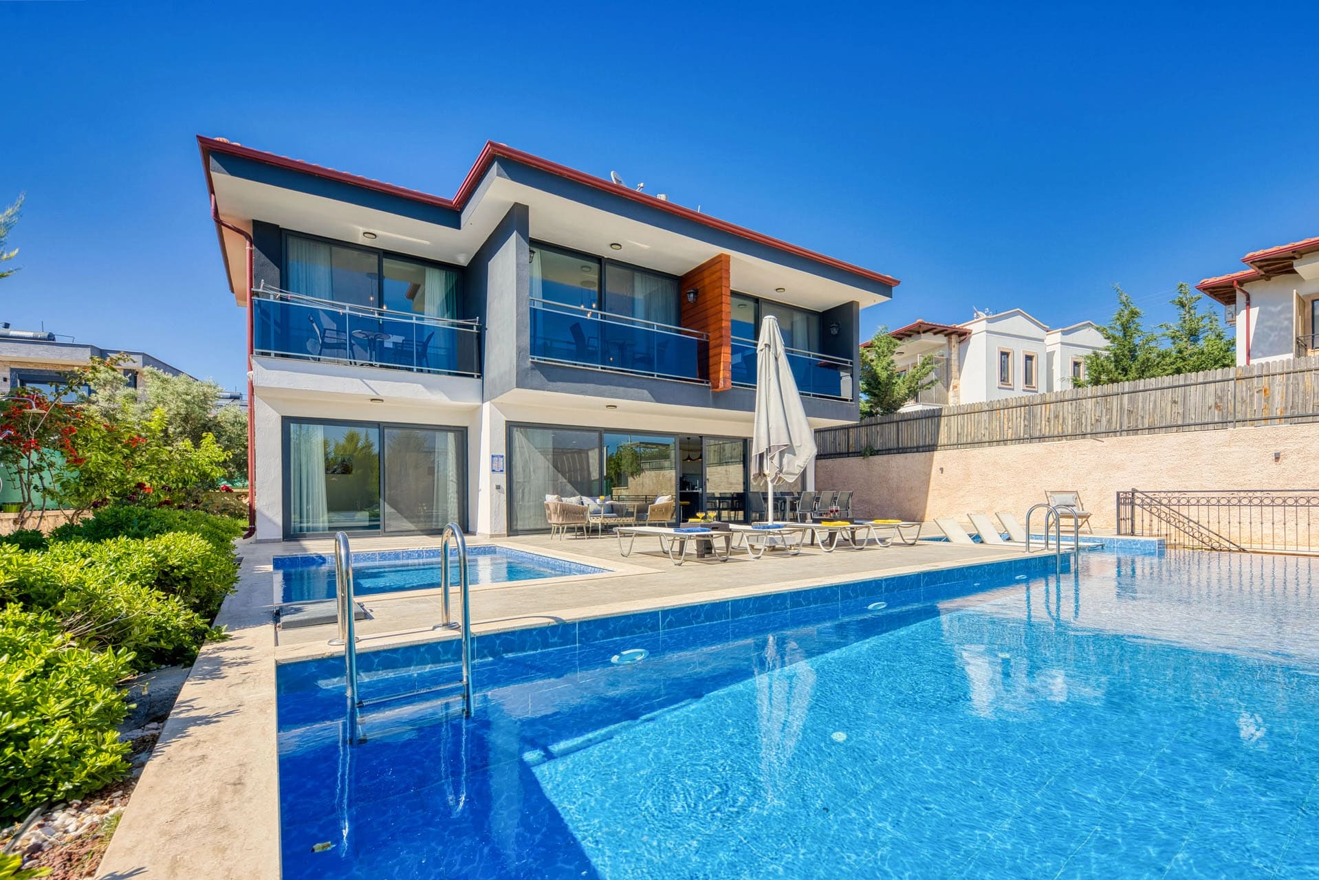 Mavi sulu açık havuzun arkasında iki katlı villa