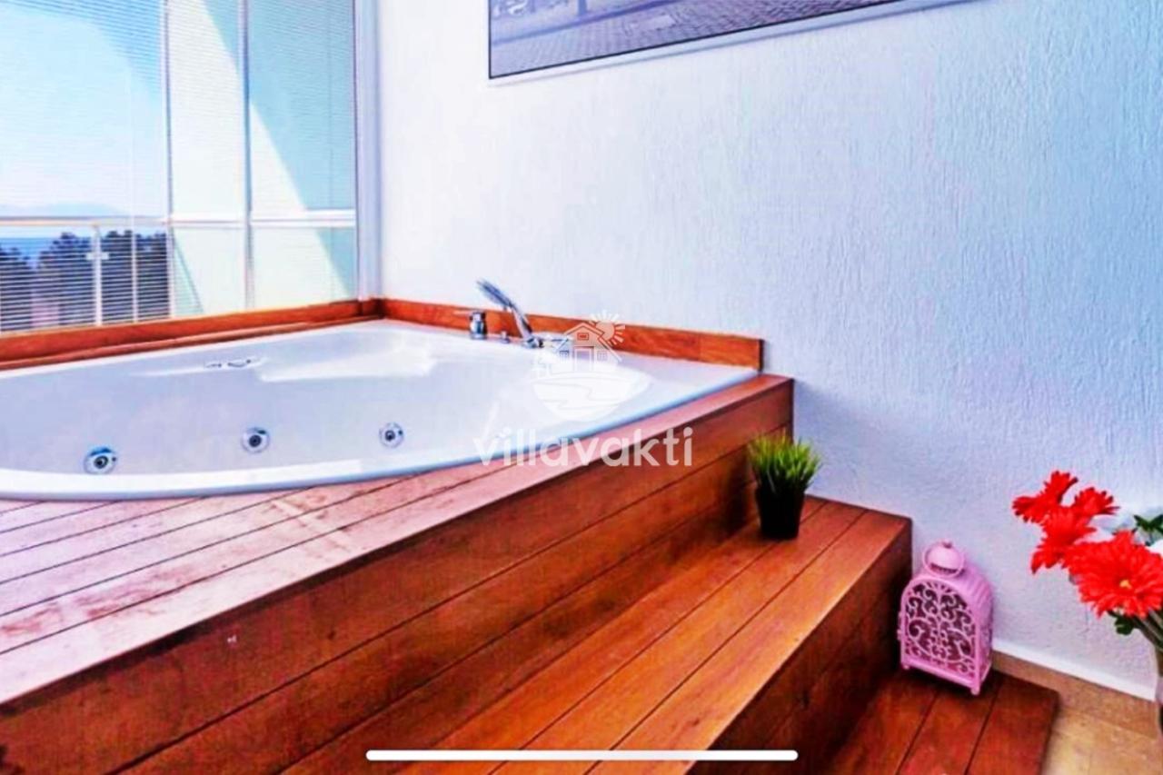 Ahşap kaplamalı yükseltilmiş platform üzerinde beyaz köşe jakuzi.