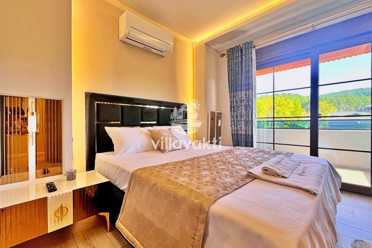 Çift kişilik yatak, led aydınlatmalı başlık, klima ve balkon kapısı olan yatak odası.