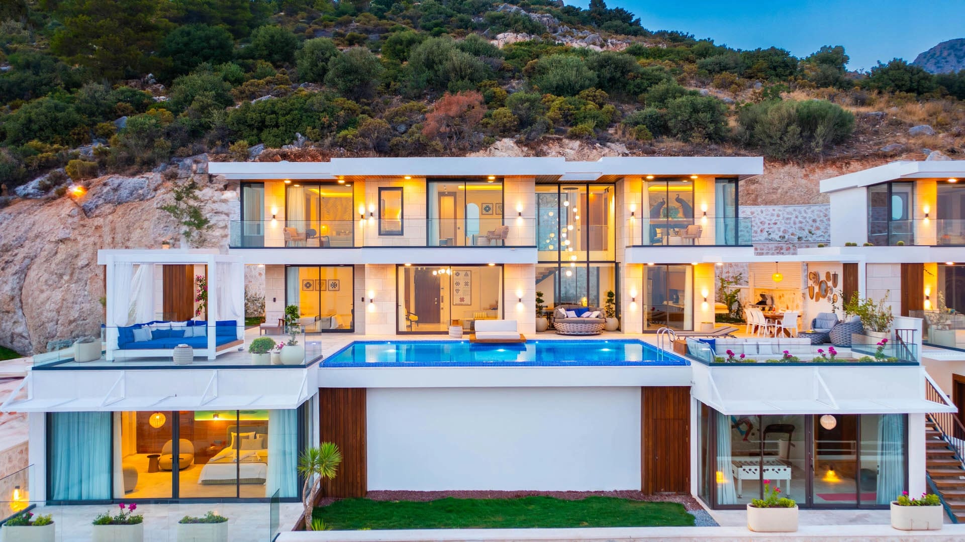 Dağ yamacında modern mimarili, sonsuzluk havuzlu ve geniş cam cepheli lüks villa.