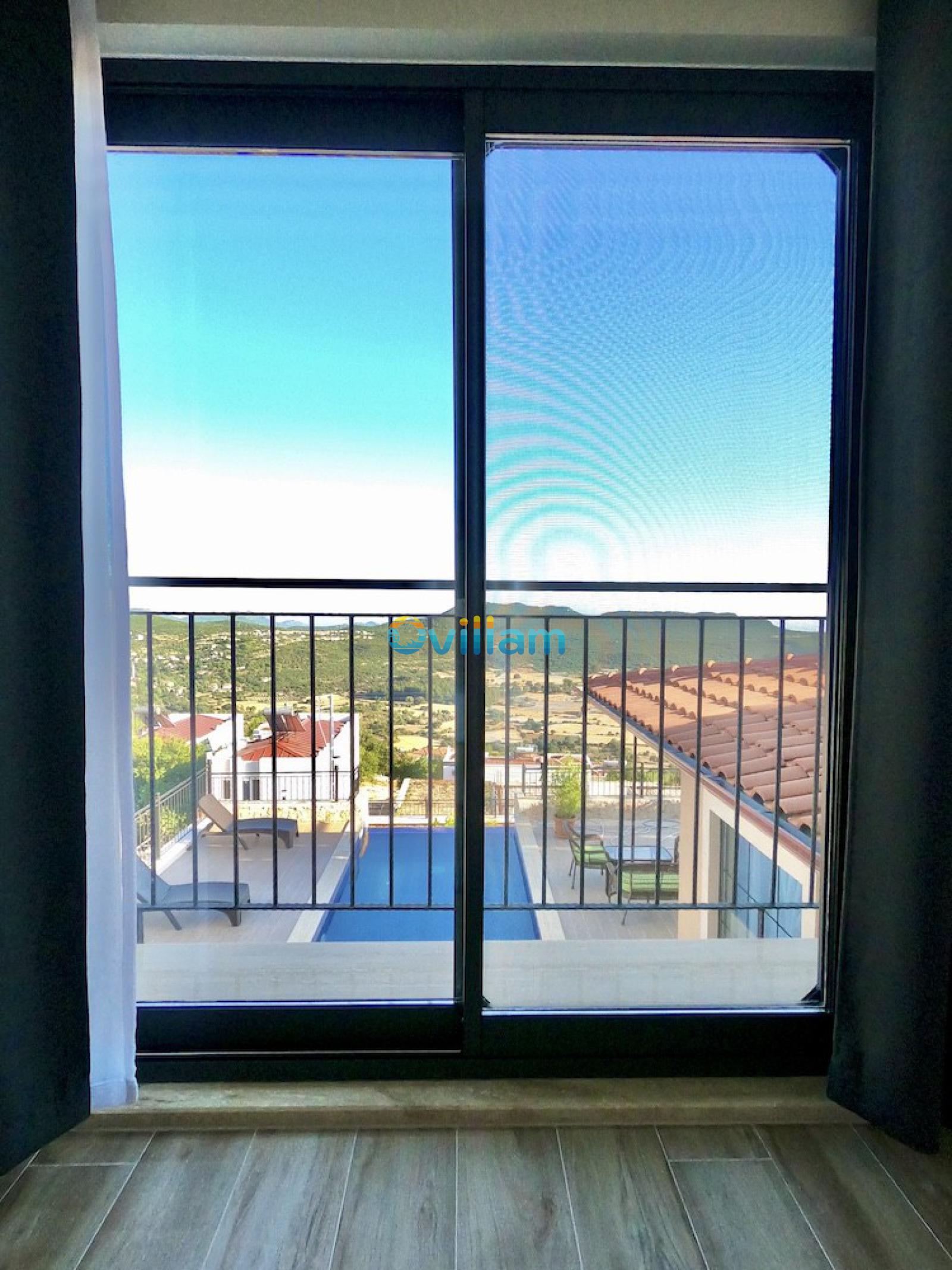 Cam kapıdan görünen dağ manzarası, havuz ve çatı kiremitleri.