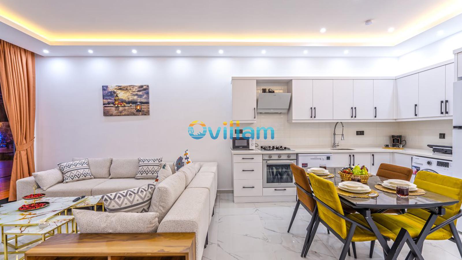 Modern mutfak, yemek masası ve oturma grubunun bir arada olduğu açık plan salon.