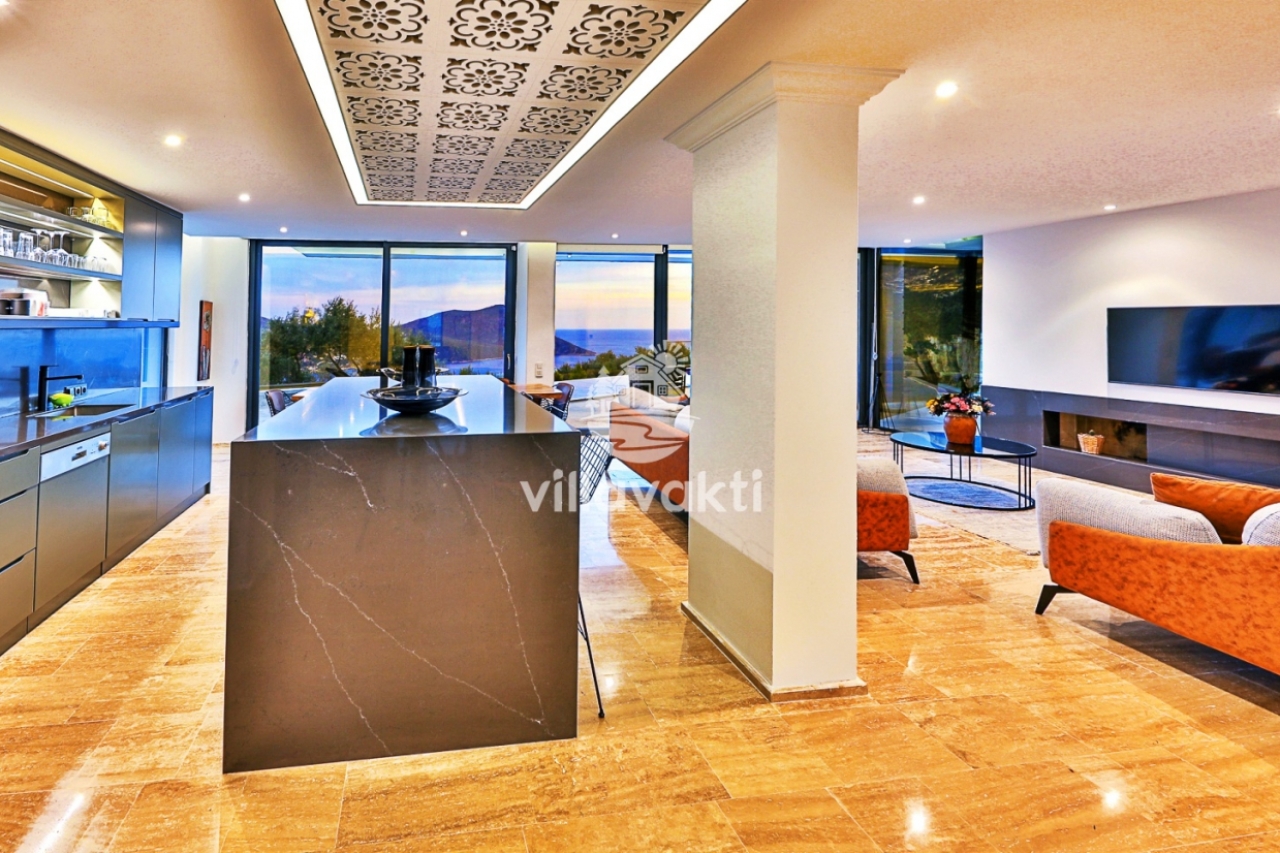 Modern mutfak adası, oturma grubu ve deniz manzaralı geniş cam pencereleri olan açık plan salon.
