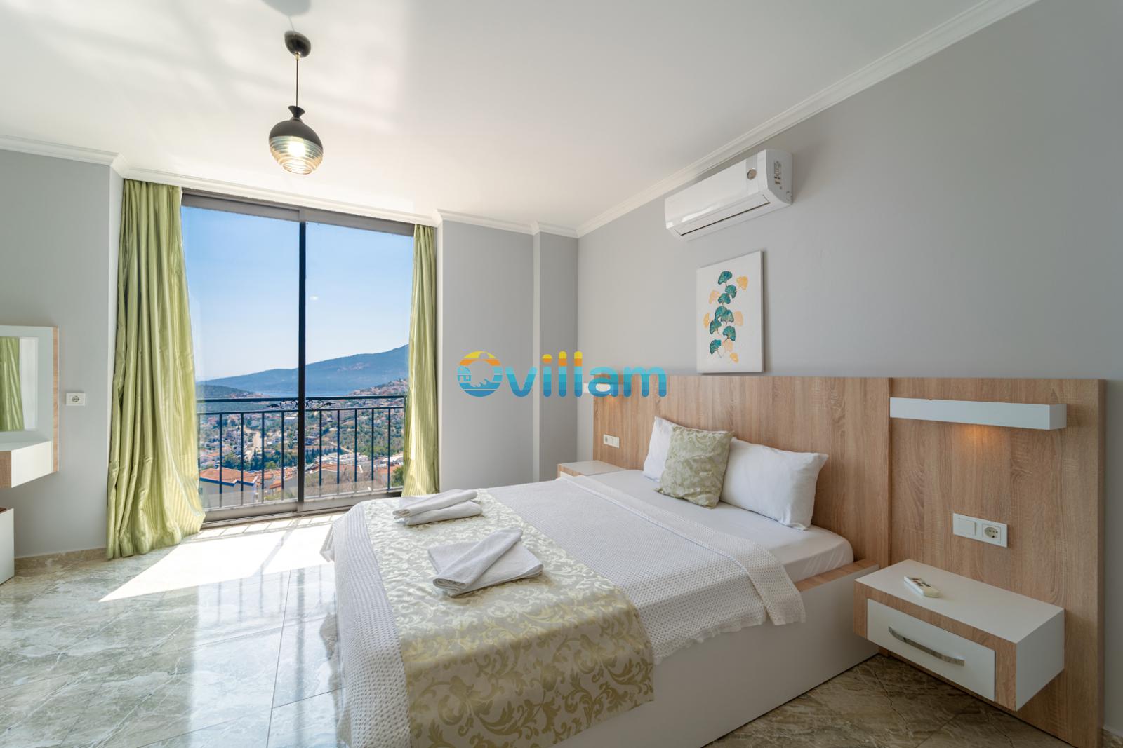 Deniz manzaralı geniş pencereli, çift kişilik yataklı ve ahşap başlıklı modern yatak odası.