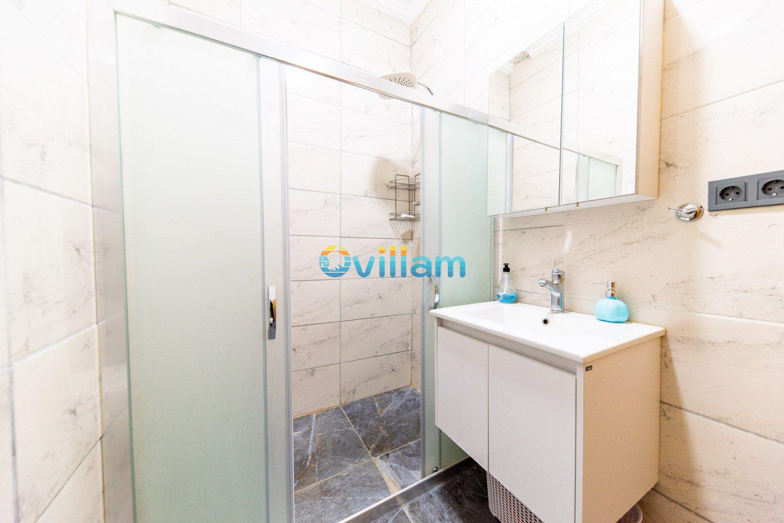 Beyaz banyo dolabı, aynalı üst modül ve cam bölmeli duş kabini.