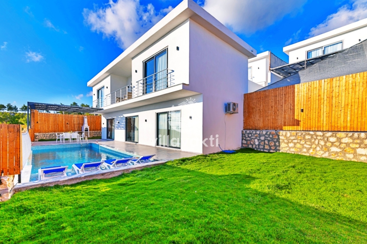 Geniş çim bahçeli, havuzlu ve iki katlı modern beyaz villa dış cephesi.