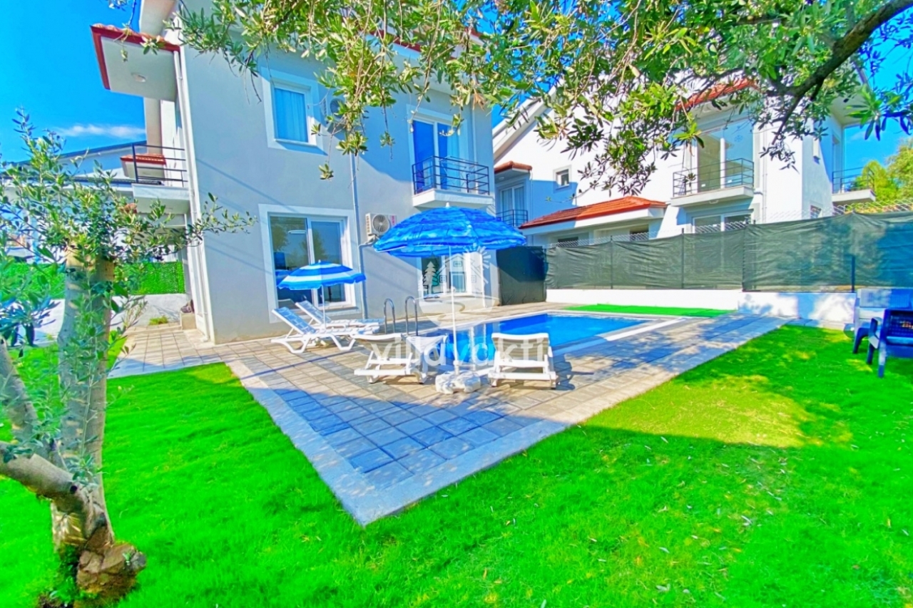 Yeşil çim bahçe ortasında yer alan yüzme havuzlu iki katlı müstakil villa.