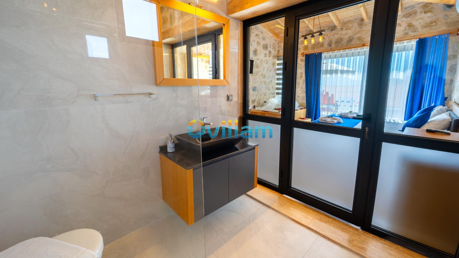 Ahşap aynalı tezgah, siyah lavabo ve cam duşakabin bulunan modern banyo.