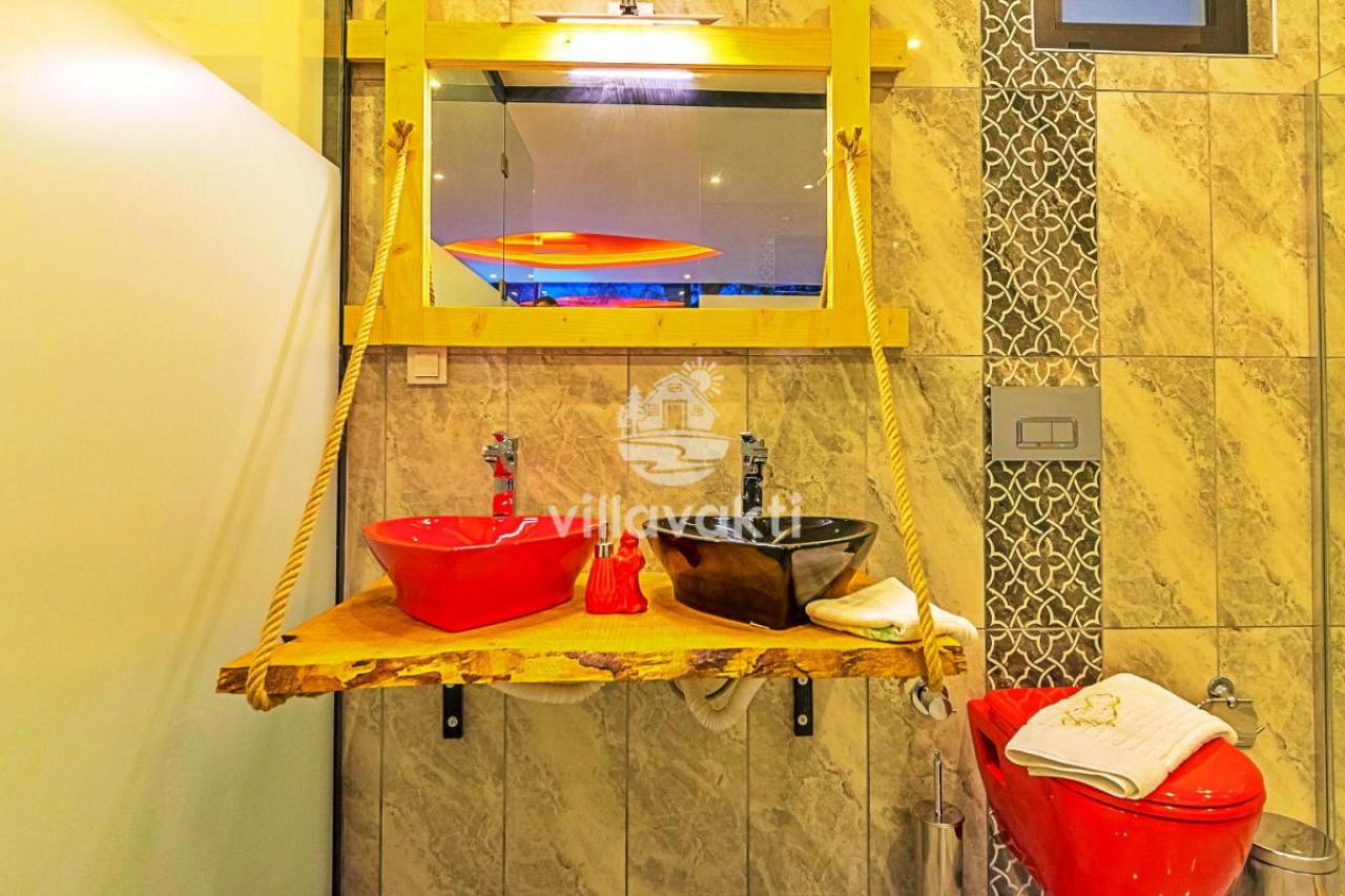 Halatlı ahşap tezgahta kırmızı ve siyah lavabolar ile kırmızı klozetli banyo.
