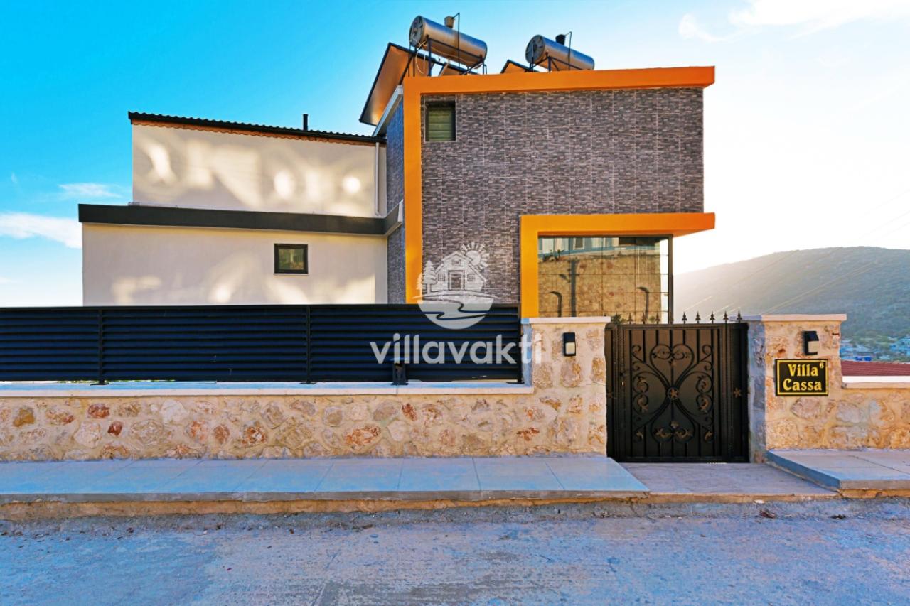 Taş duvar, demir kapı ve üzerinde Villa Cassa yazan tabela bulunan bina dış cephesi.