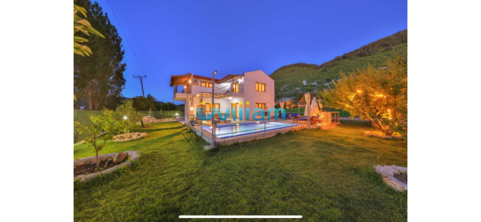 Bahçesi aydınlatılmış ve havuzu olan iki katlı villa.