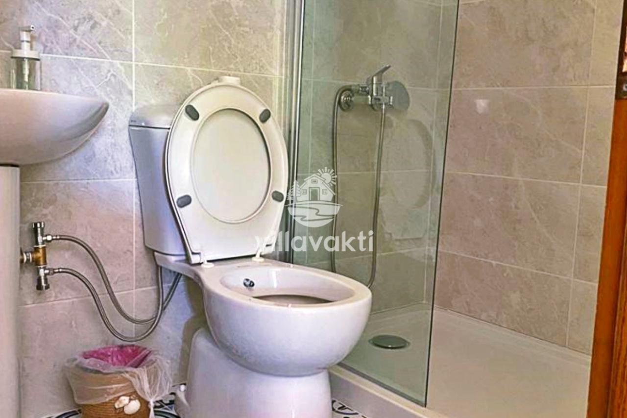 Bej seramik kaplı banyoda klozet, duşakabin ve lavabo yer alıyor.