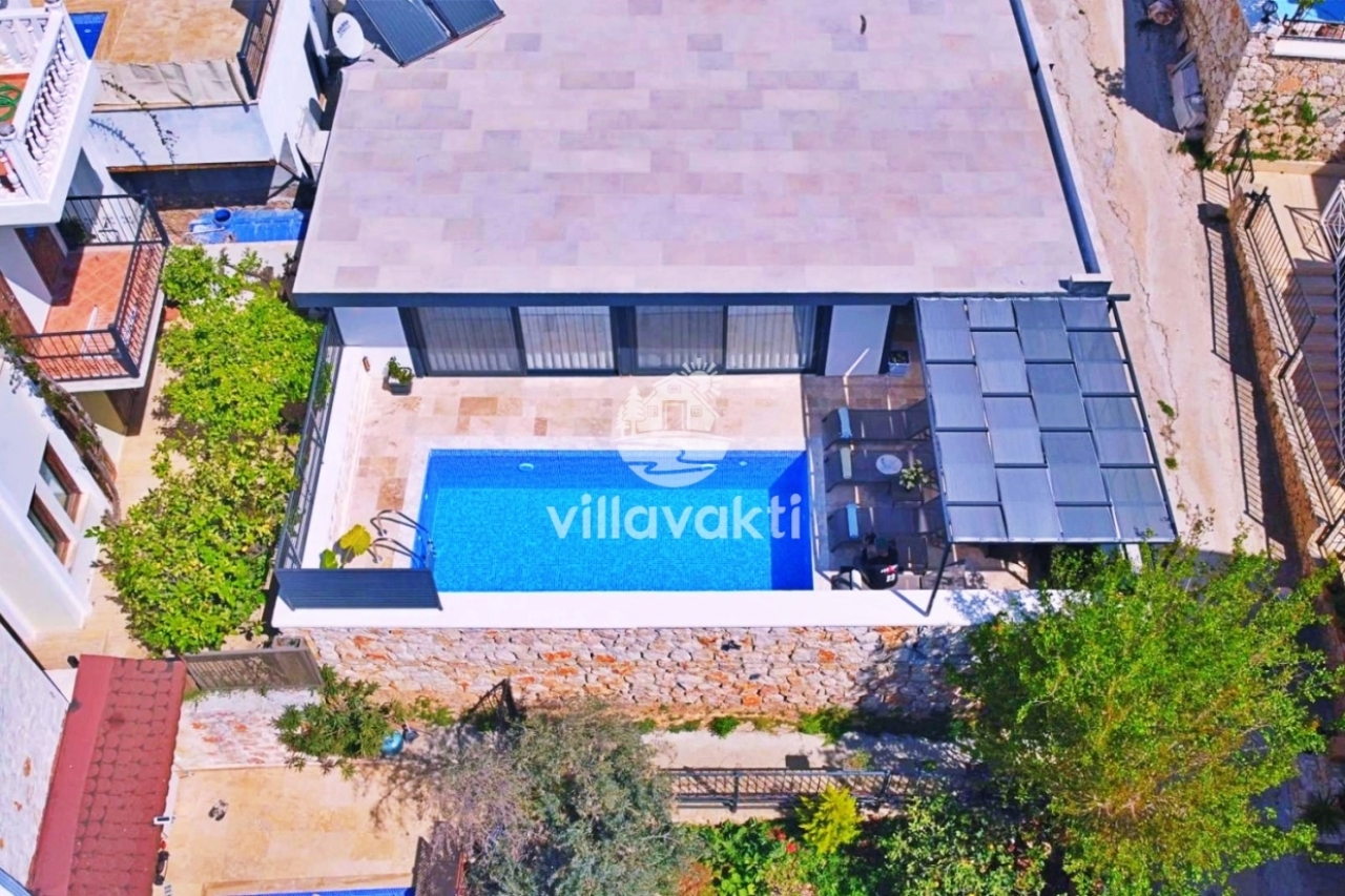 Mavi havuzlu ve teraslı villanın havadan görünümü.