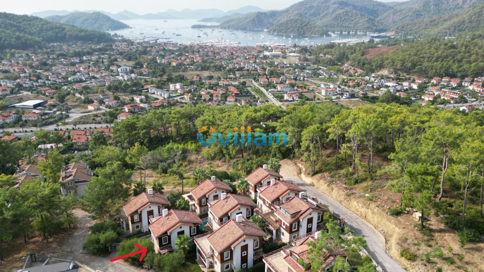 Orman içinde konumlanan villaların uzaktan deniz manzaralı genel görünümü.