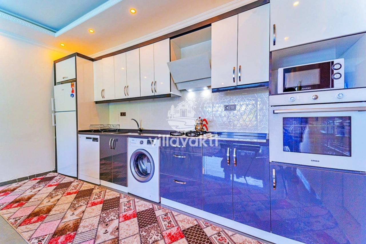 Beyaz ve mavi dolaplı, desenli halının serili olduğu modern mutfak.