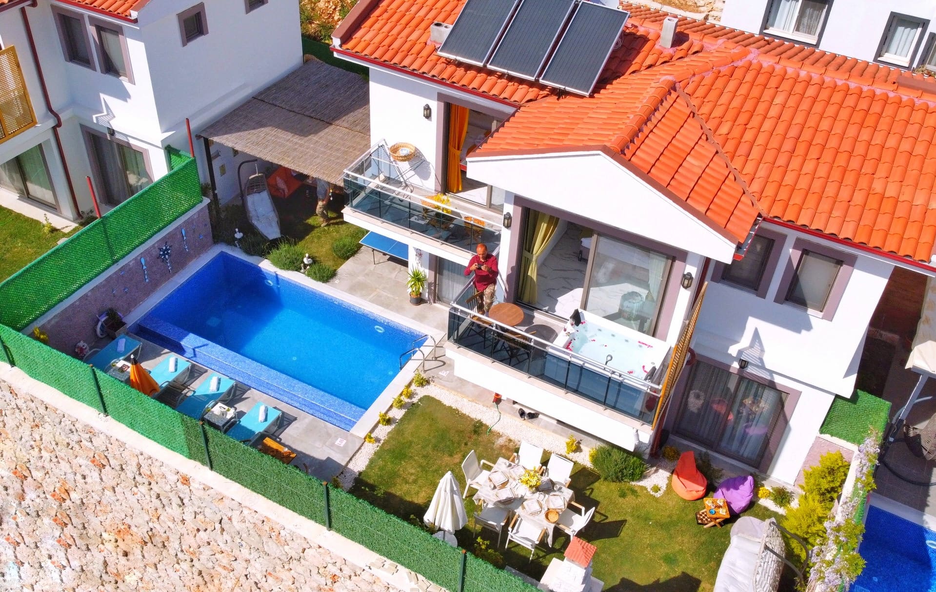 Kiremit çatılı iki katlı villanın havuzu ve bahçe yemek masası.