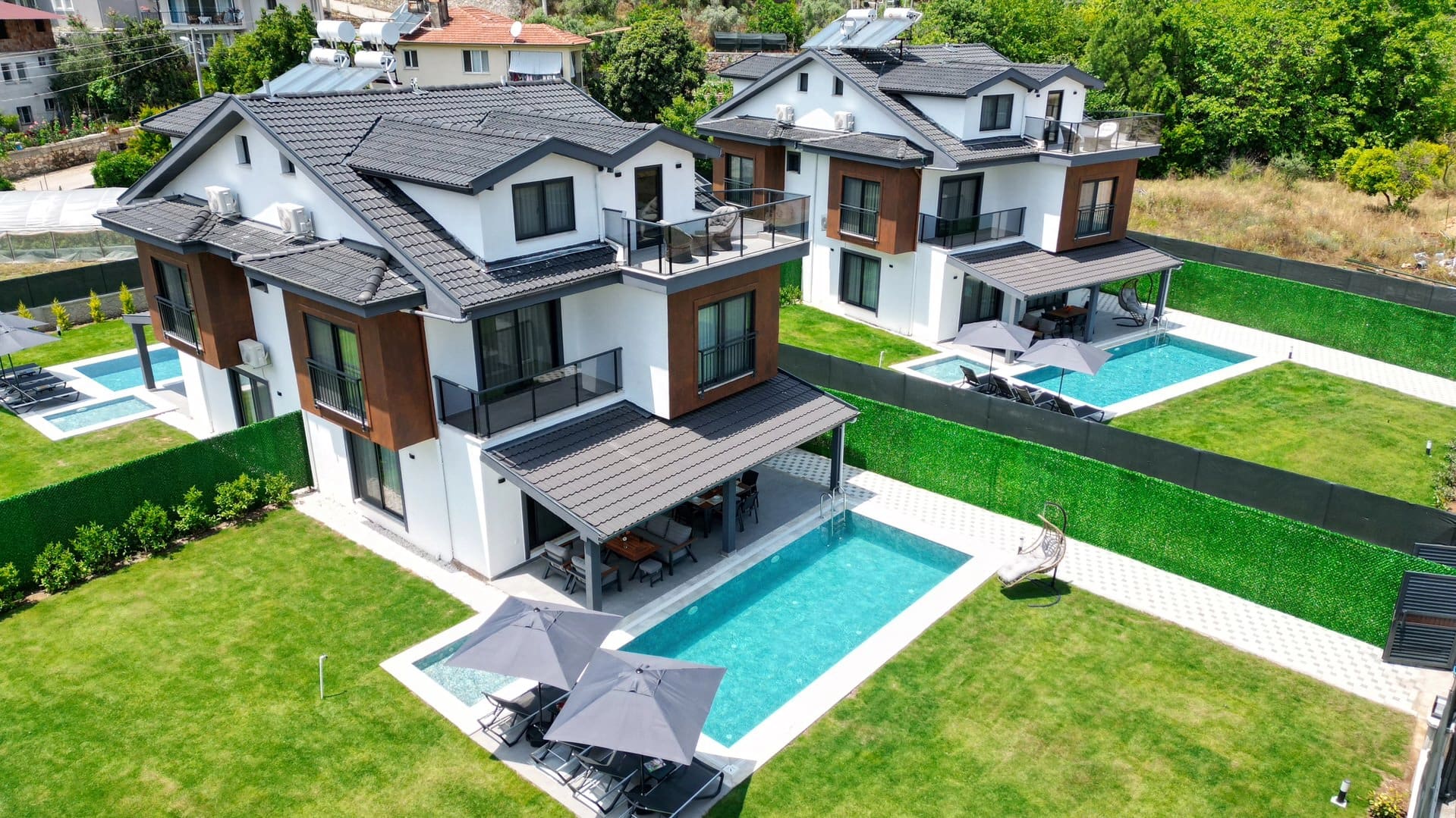 Yeşillikler içindeki bahçesi ve havuzu olan modern villa dış cephesinin yüksekten görünümü.