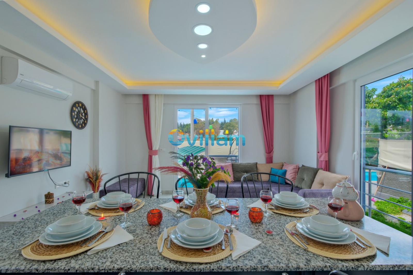 Ön planda şık bir yemek masası, arka planda ise oturma grubu olan aydınlık salon.