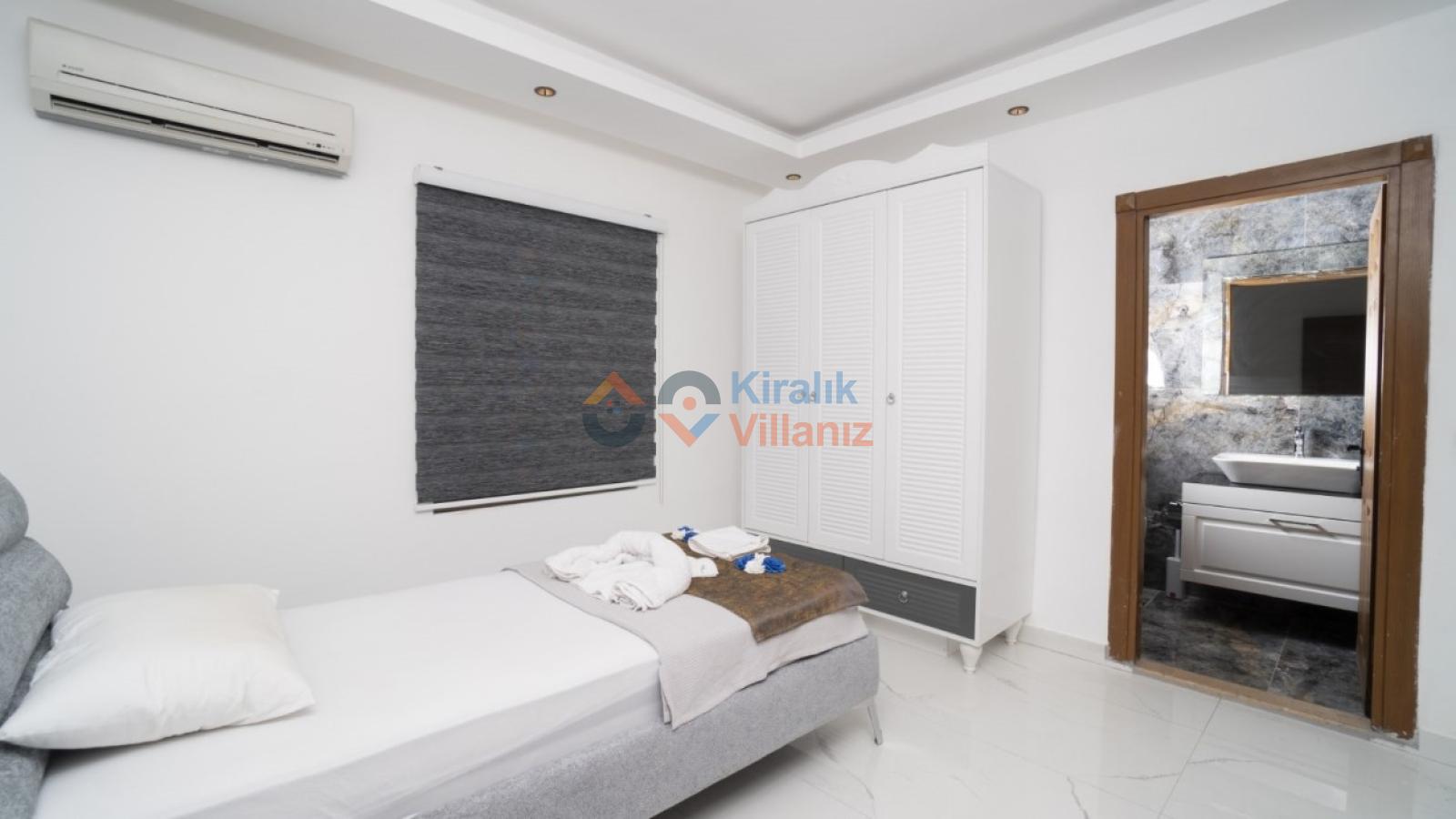 Tek kişilik yatak, gardırop ve açık banyo kapısı görünen yatak odası.