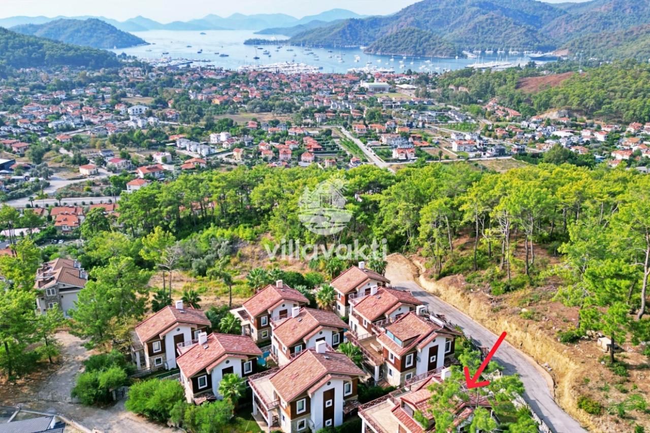 Ağaçlar arasında konumlanmış villaların üzerinden deniz ve kıyı şeridi görünür.