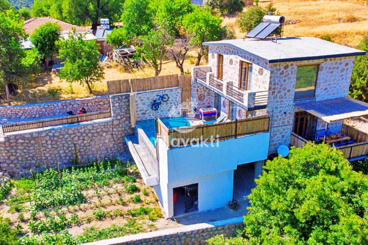 Taş duvarlı bahçesi ve havuzu olan taş kaplamalı iki katlı villa.
