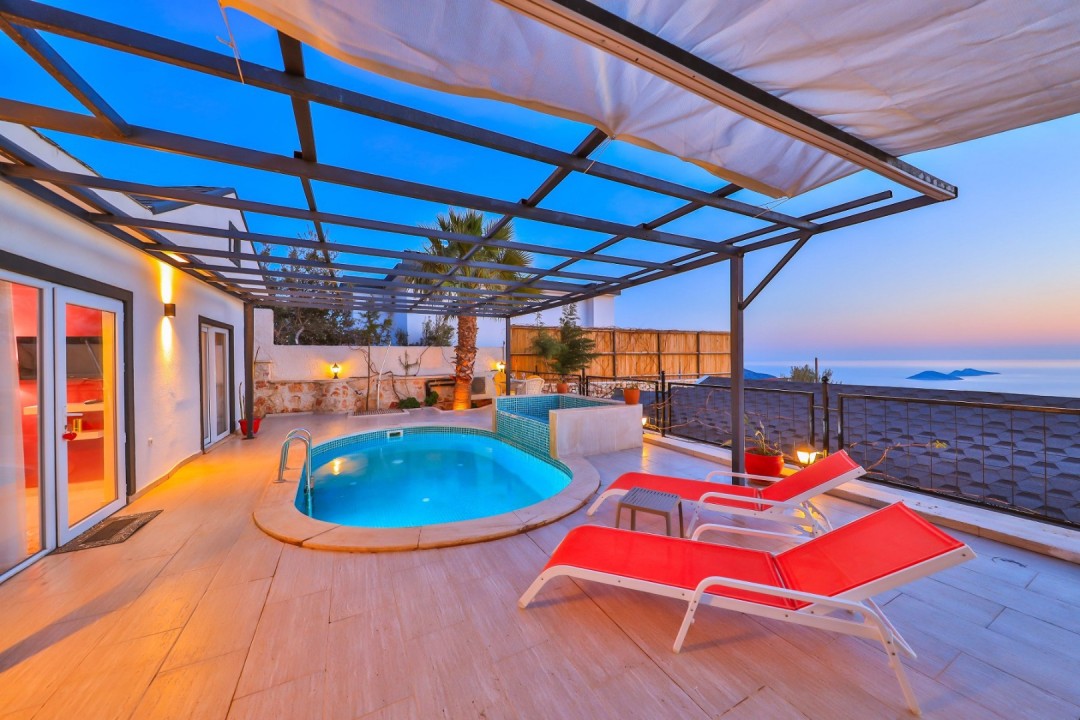 Akşam vakti havuz ve şezlongların bulunduğu, ferforje tavanlı villa terası.