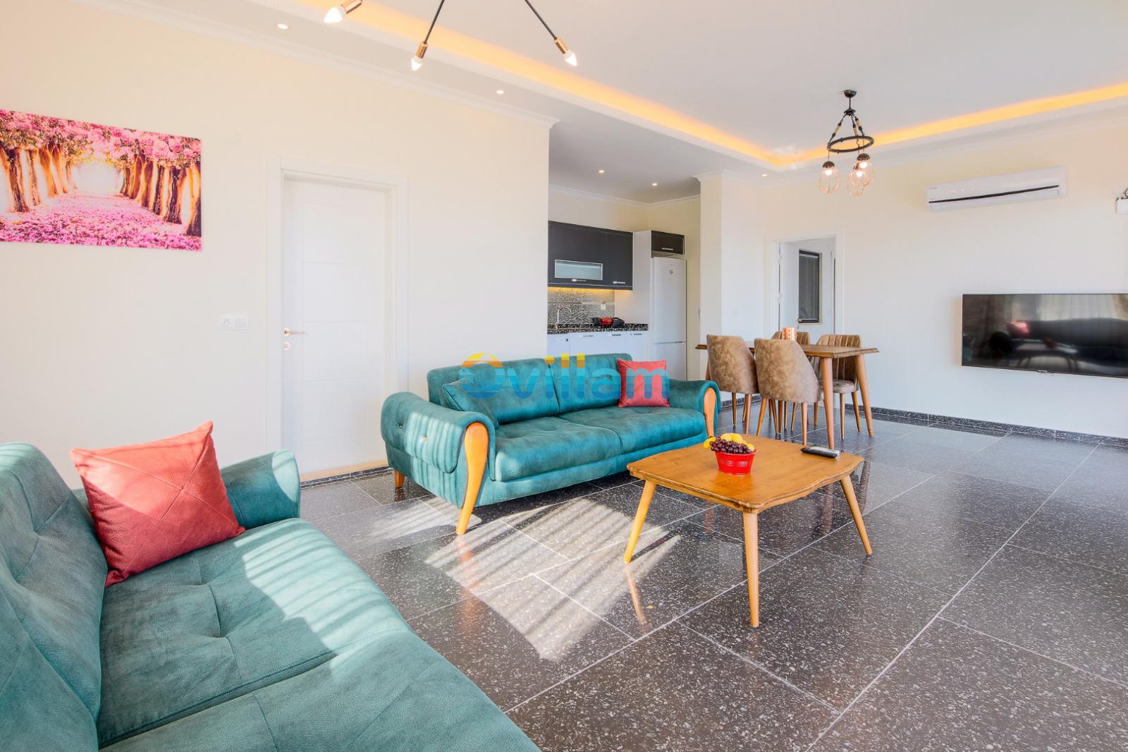 Yeşil koltuk takımı ve ahşap yemek masası bulunan modern salon.