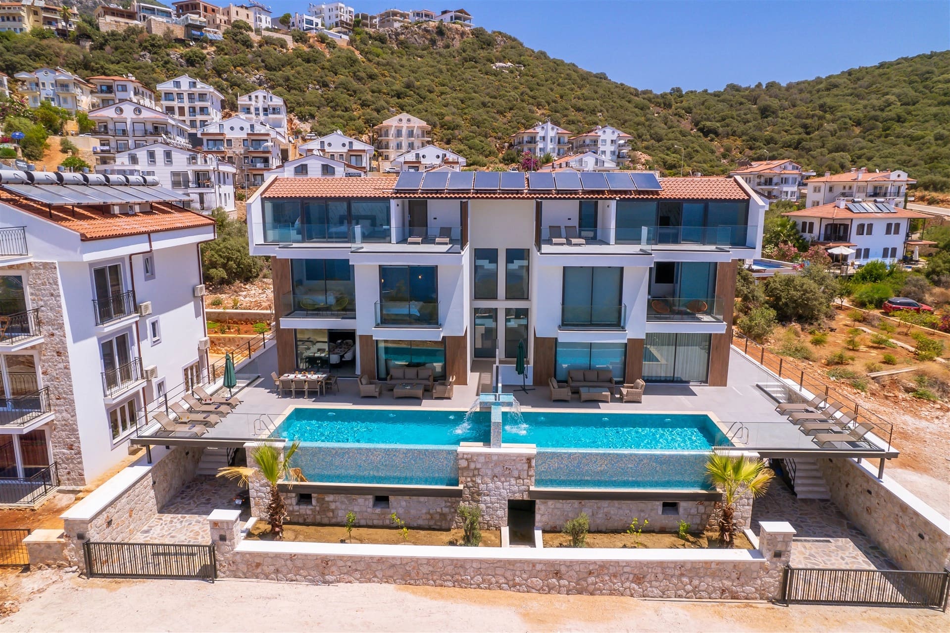 Dağ eteklerindeki modern villanın dış cephesi ve önündeki havuz.