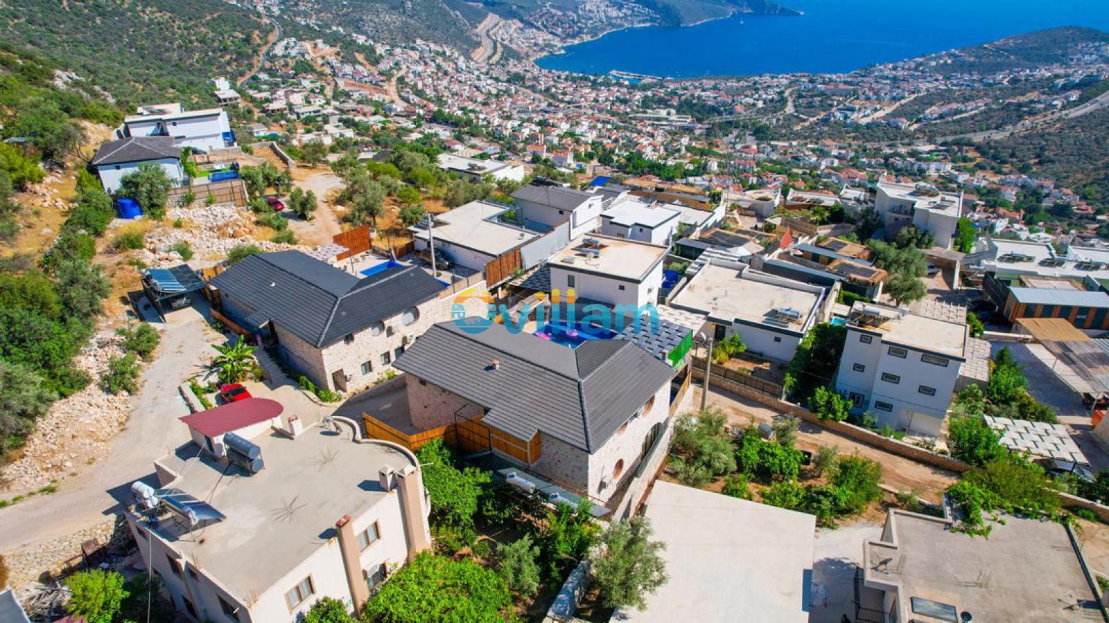 Yüksekten villaların ve uzaktaki denizin kuş bakışı görünümü.