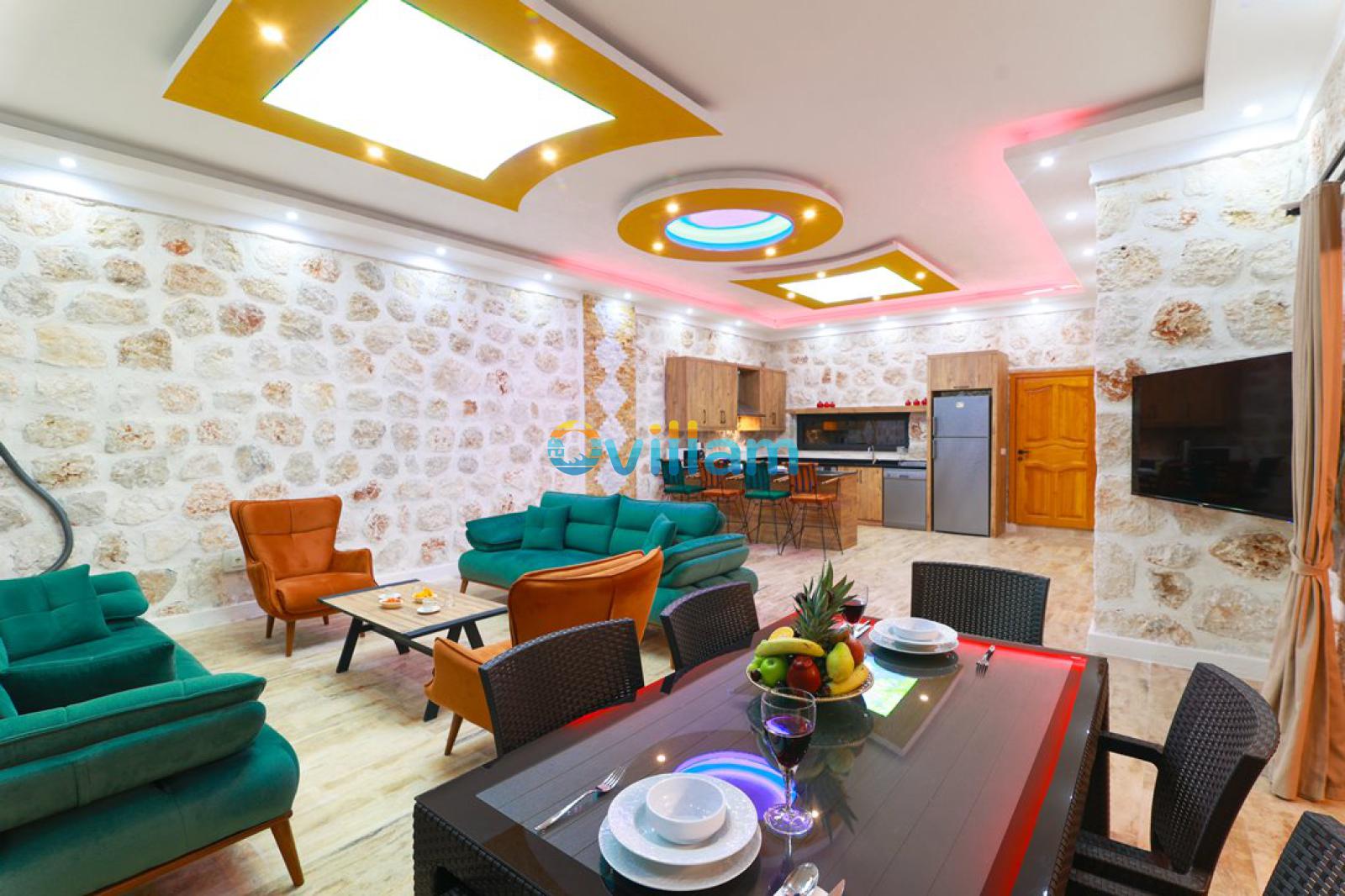 Taş duvarlı, oturma grubu ve yemek masası bulunan geniş iç mekan.
