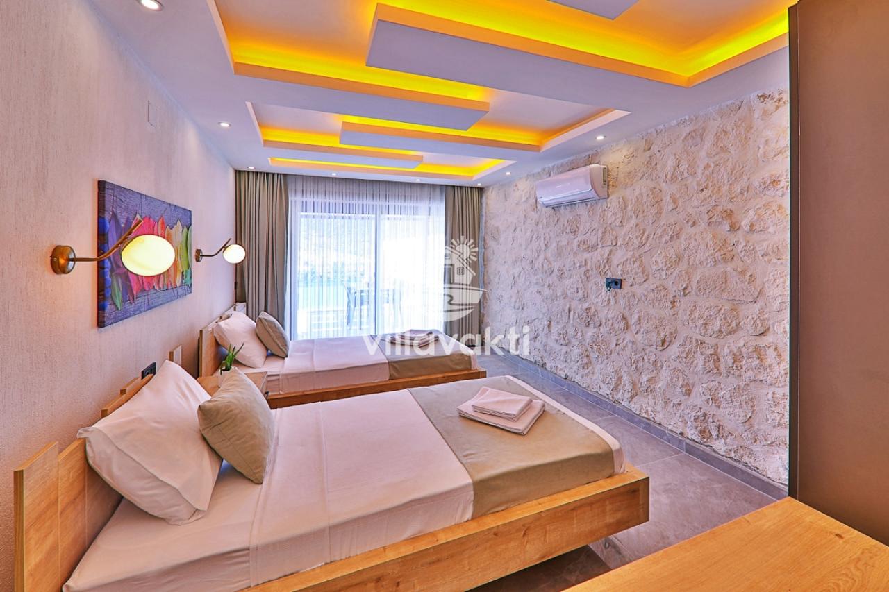 Ahşap yatak başlıkları ve taş duvar detayına sahip yatak odası.