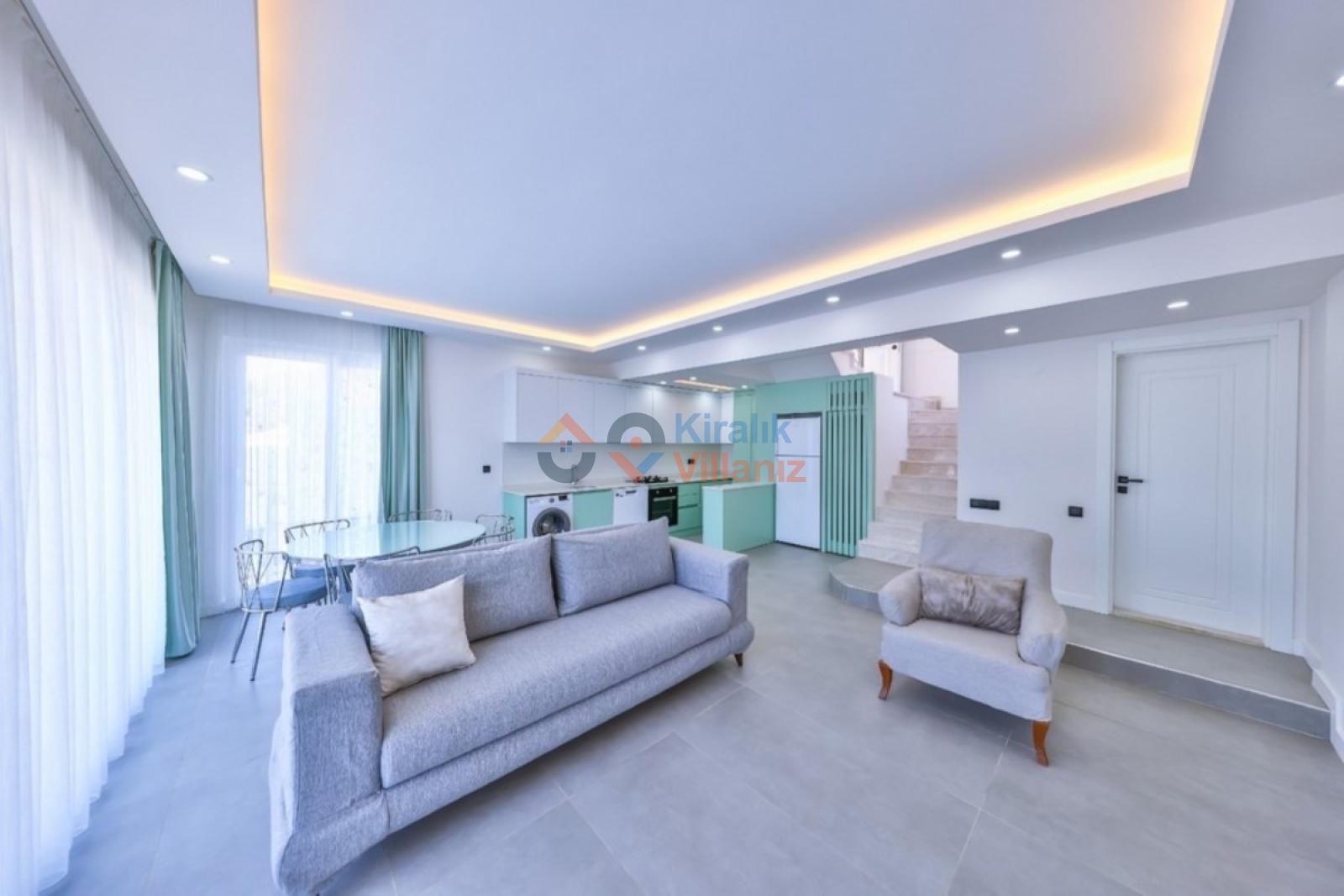 Gri koltuk takımı ve açık mutfak bulunan modern oturma odası.