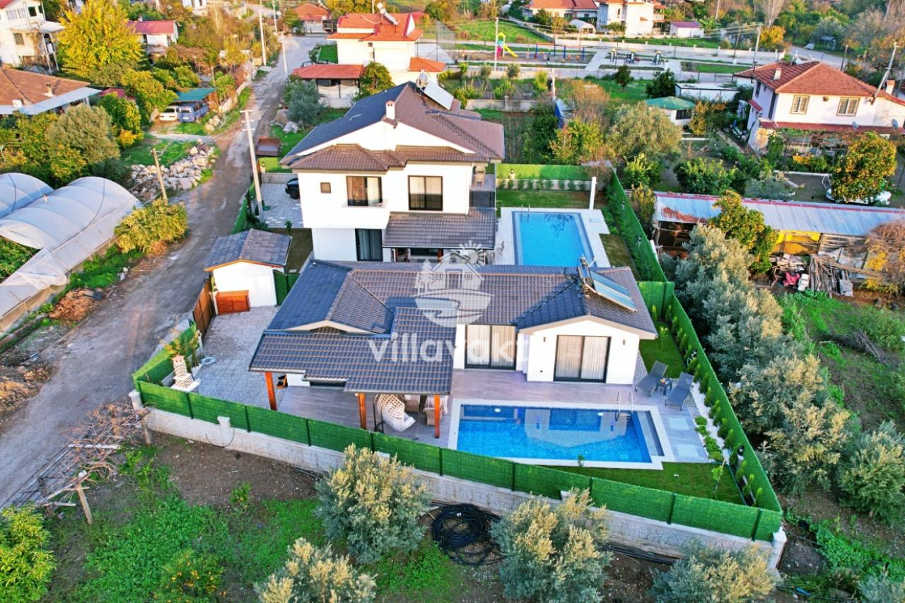 İki katlı villa, havuzları ve yeşil bahçesiyle yukarıdan görünüm