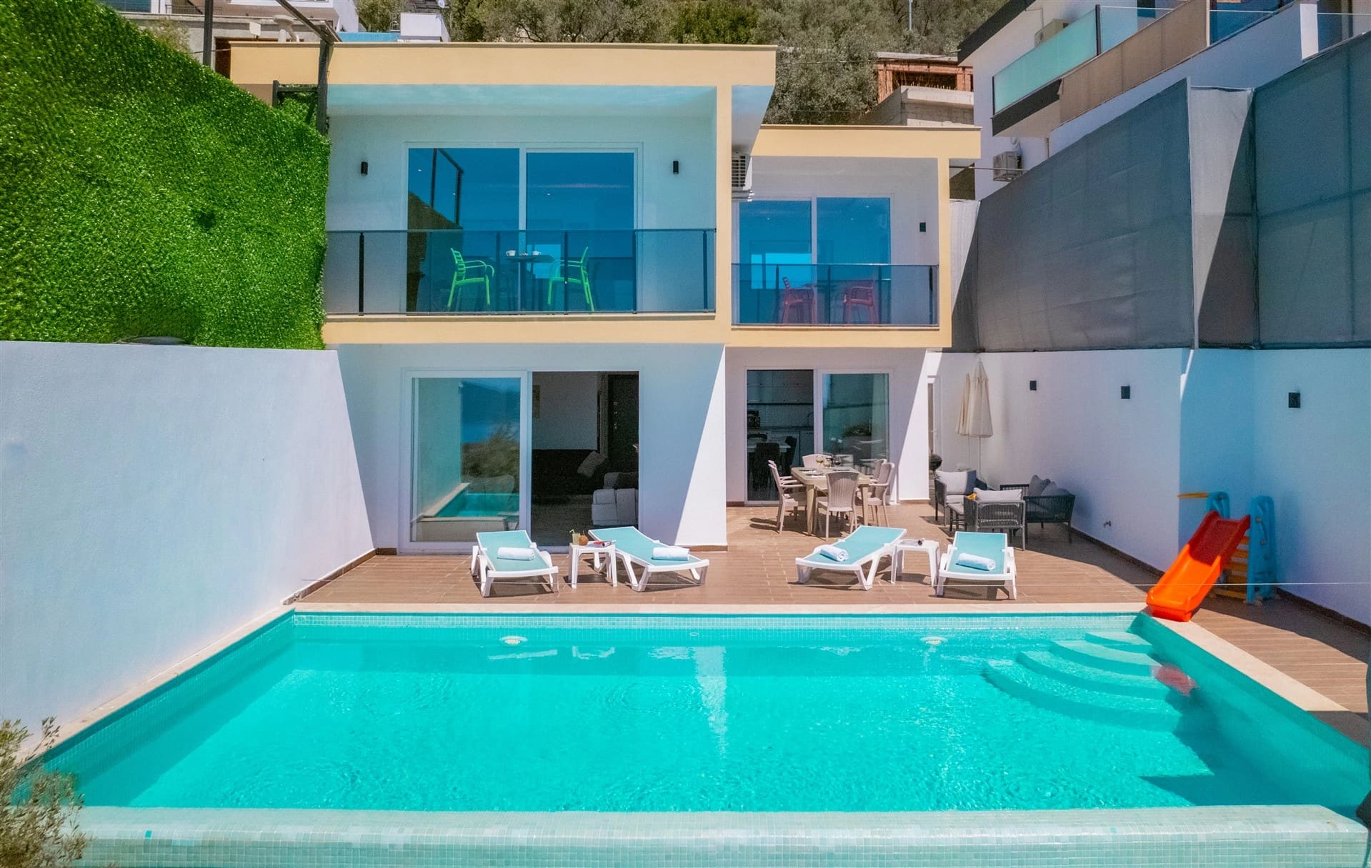 Önünde havuz ve şezlonglar bulunan iki katlı villa dış cephesi