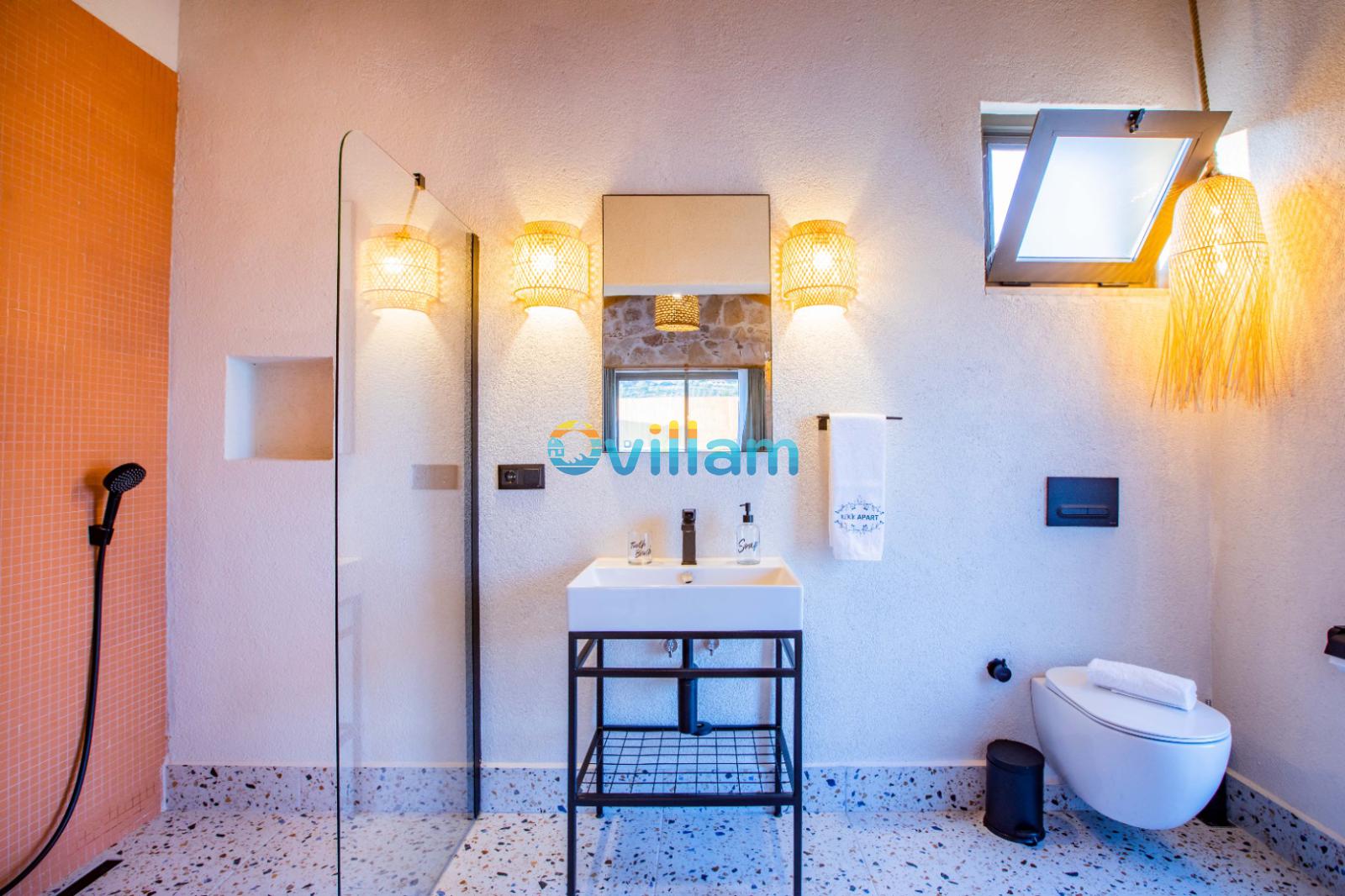 Ahşap hasır avizeli, turuncu duvarlı, duşakabinli ve klozetli modern banyo.