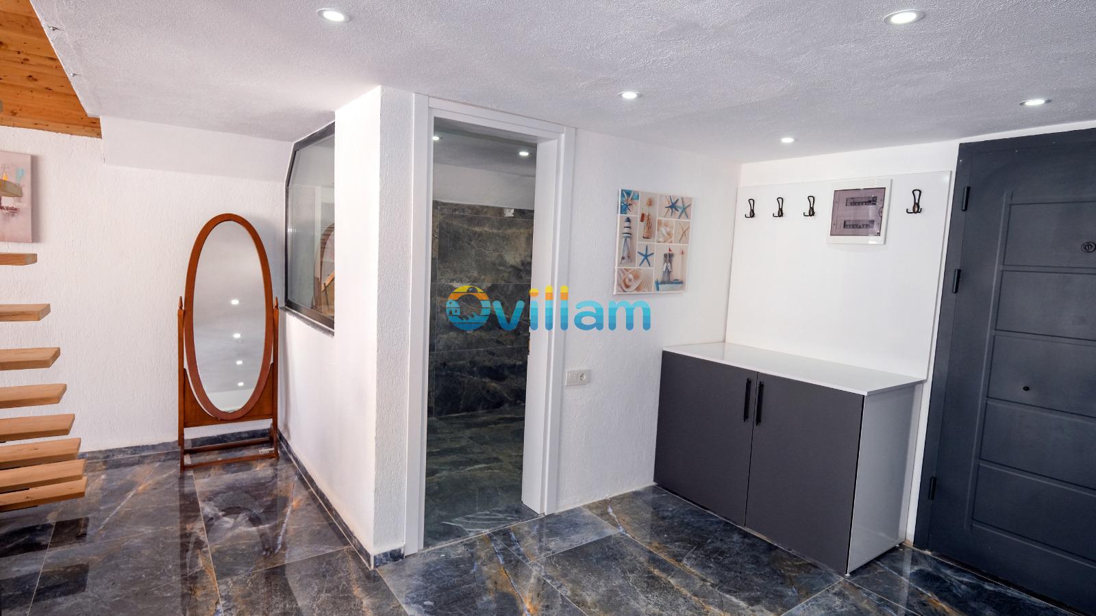 Ahşap merdivenli, mermer zeminli antrede boy aynası, vestiyer ve banyo kapısı bulunuyor.