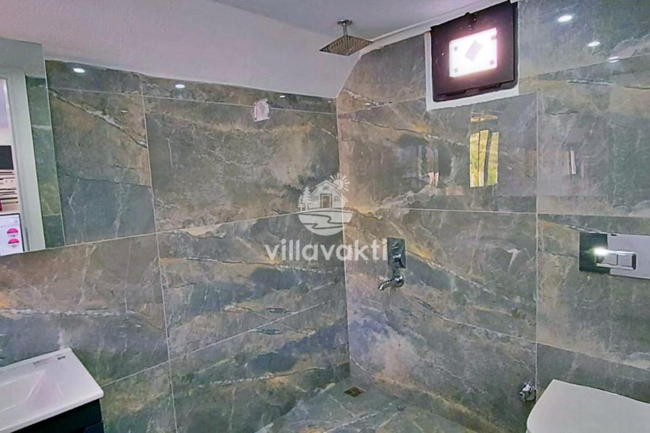 Gri mermer kaplı duvarları olan duş alanı ve lavabo.