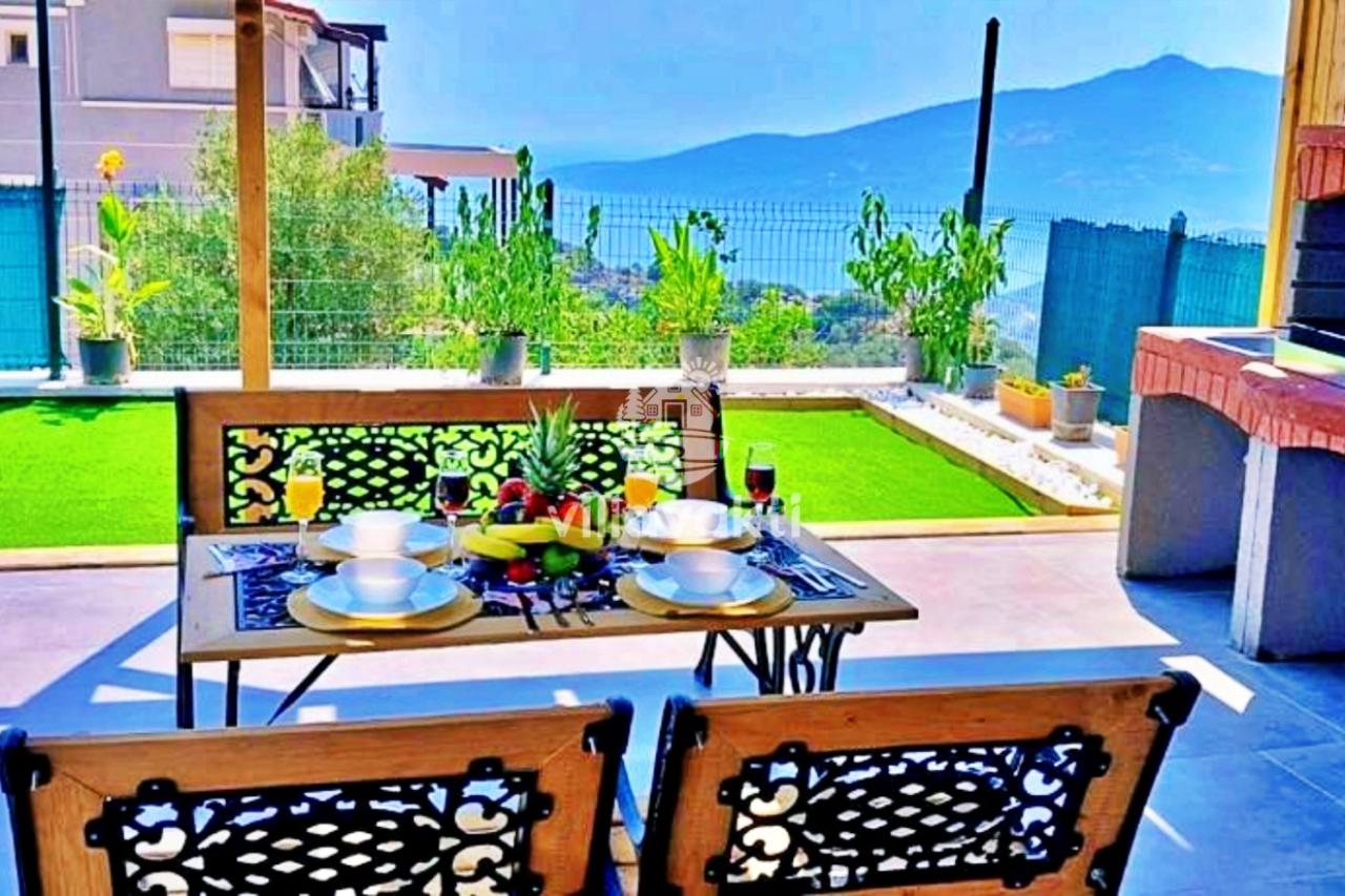Bahçede deniz manzaralı yemek masası ve barbekü alanı.