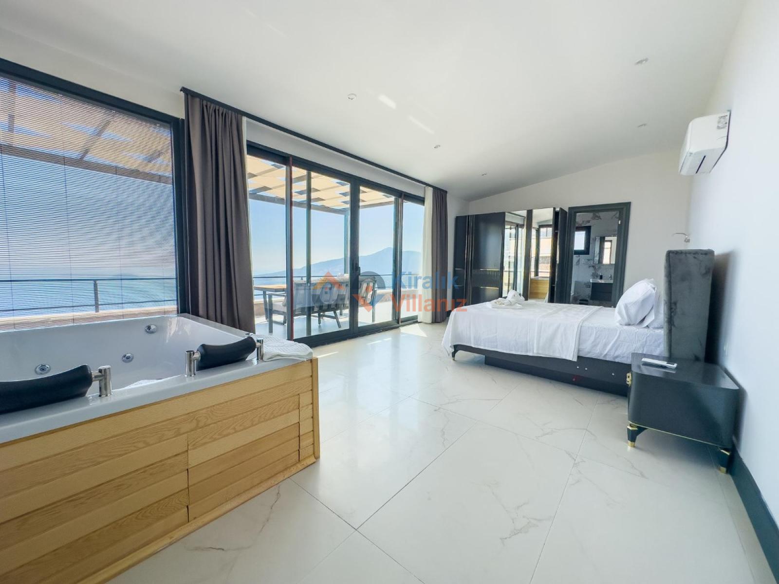 Büyük yatak ve jakuzi bulunan ferah yatak odası, cam balkon kapısı.