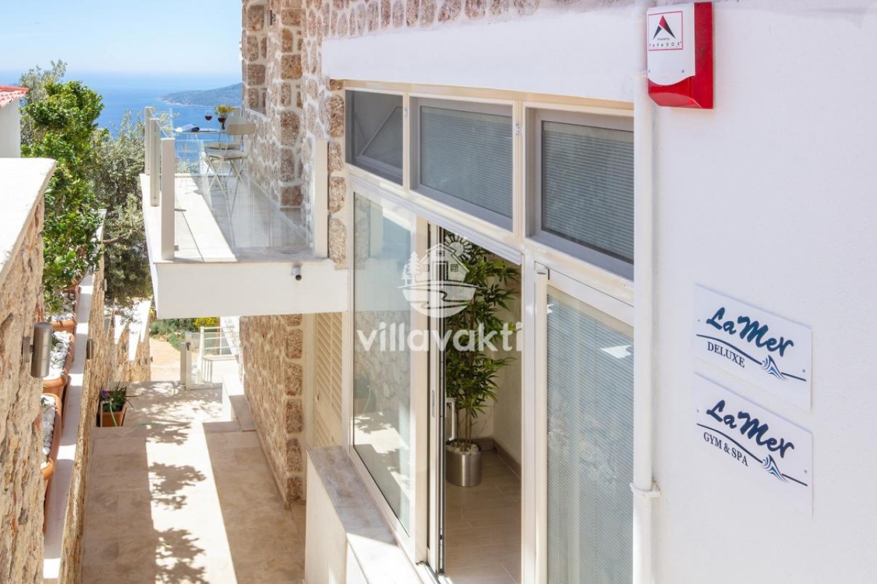 Taş duvarlı dış cephe ve ferforje korkuluklu balkon detayları.