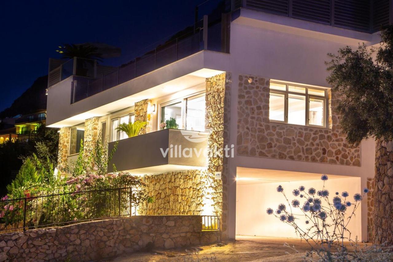 Akşam aydınlatmalı taş detaylı villanın dış cephesi.