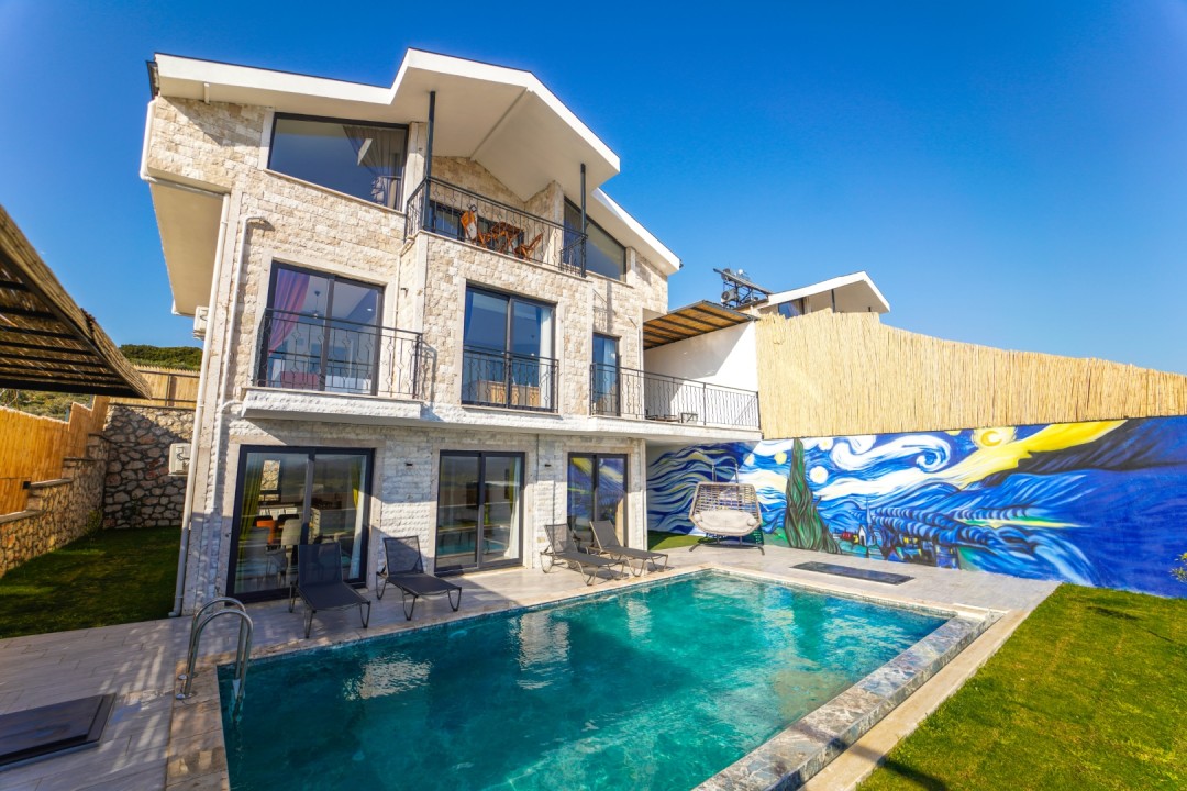 Taş kaplamalı üç katlı villa, özel yüzme havuzu, şezlonglar ve duvarında Van Gogh esintili mural bulunan bahçe.