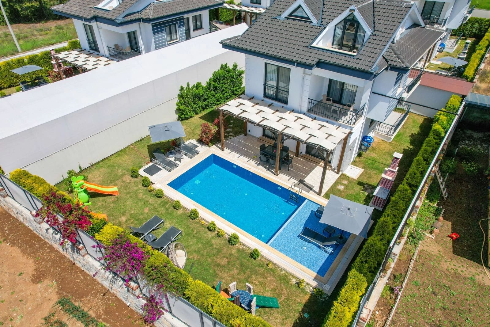 Özel havuzlu ve şezlonglu villa bahçesinin üstten görünümü.