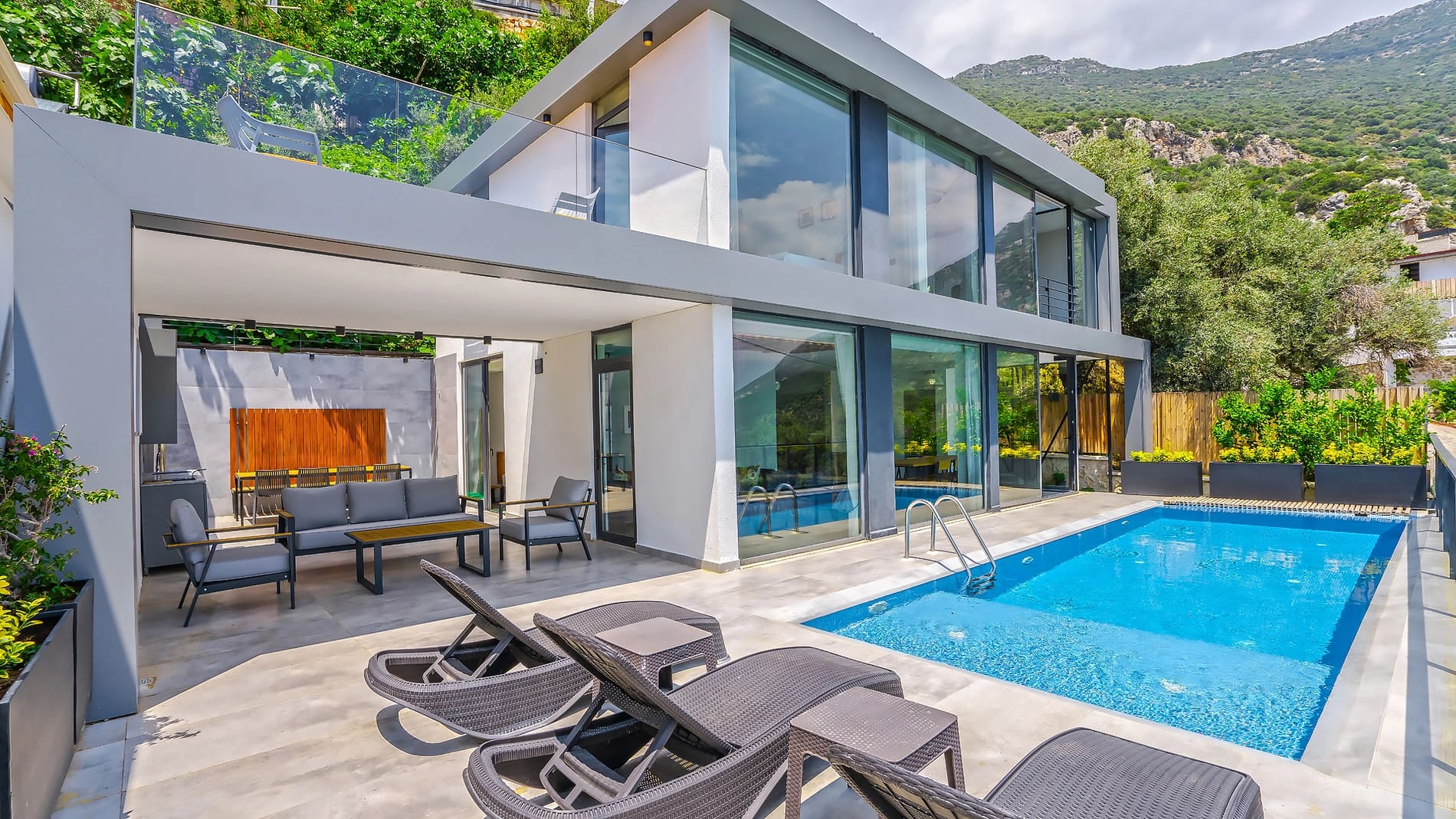 Bahçesinde havuz ve şezlonglar bulunan modern iki katlı villa.