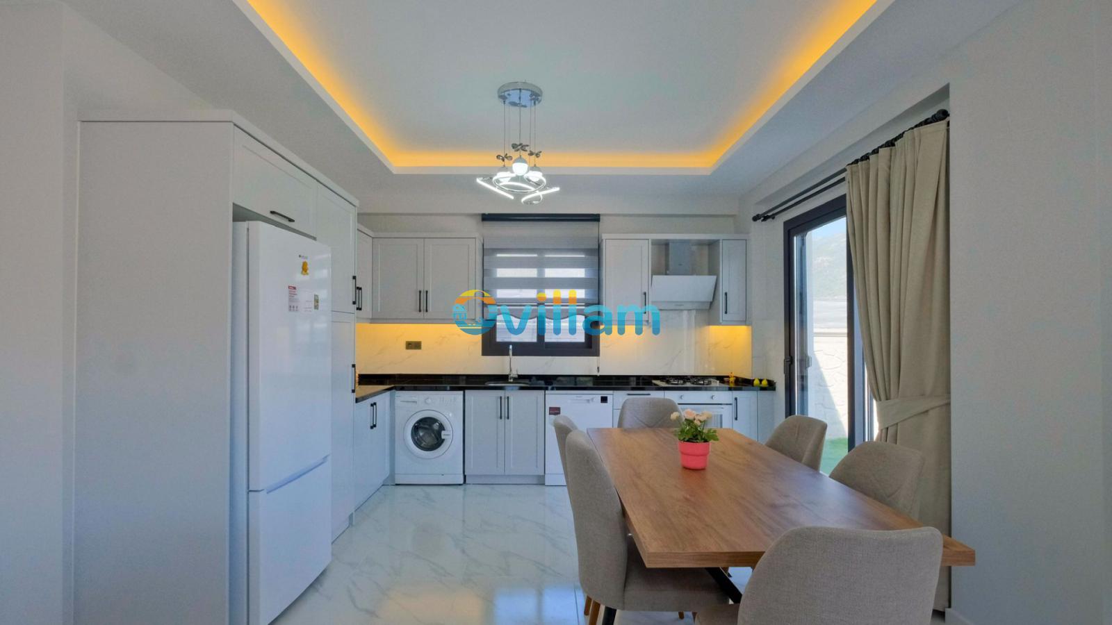 Beyaz dolaplı modern mutfak ve ahşap yemek masası.